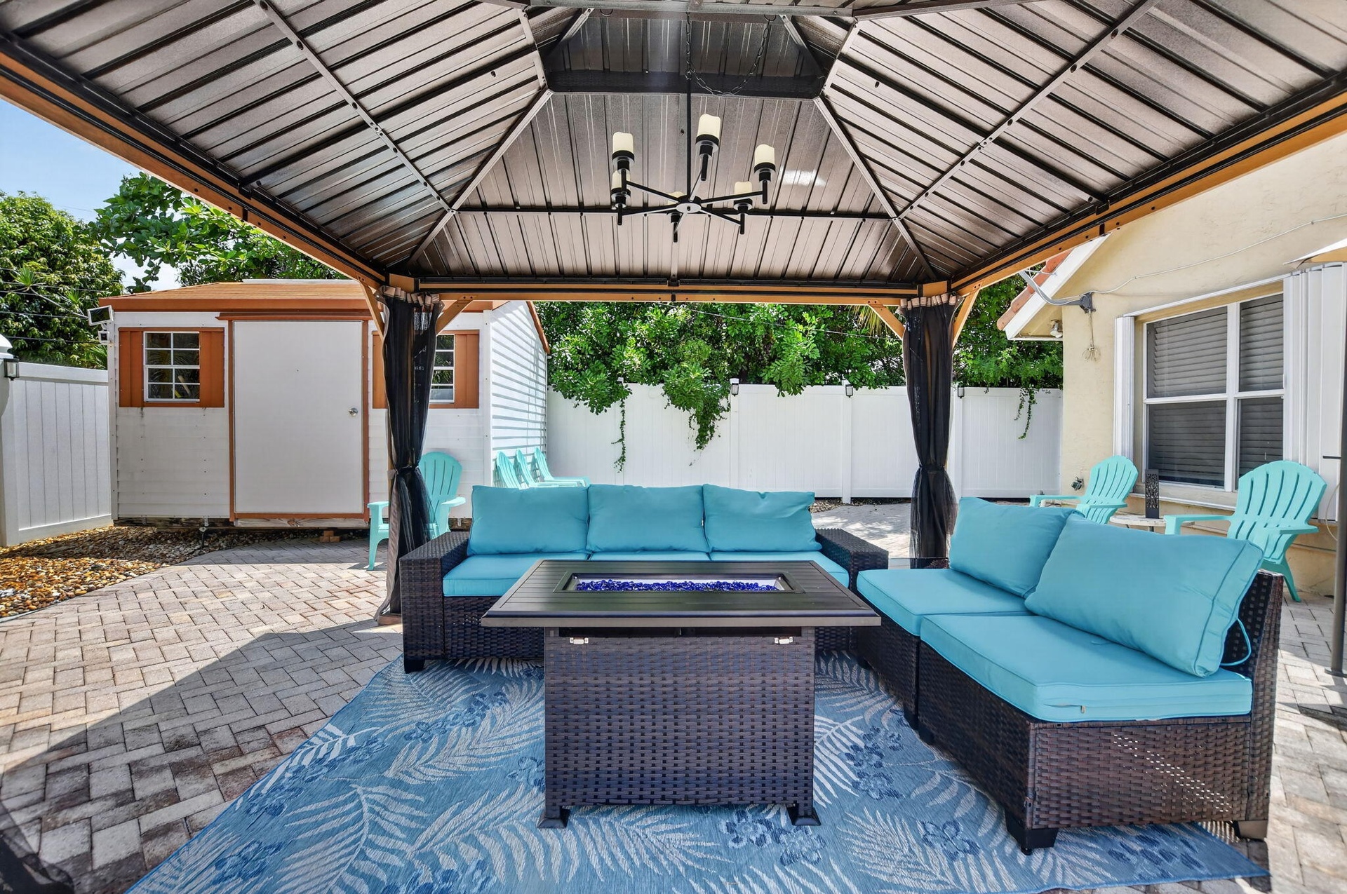 Paved patio featuring a built-in gazebo with a chandelier and privacy curtains