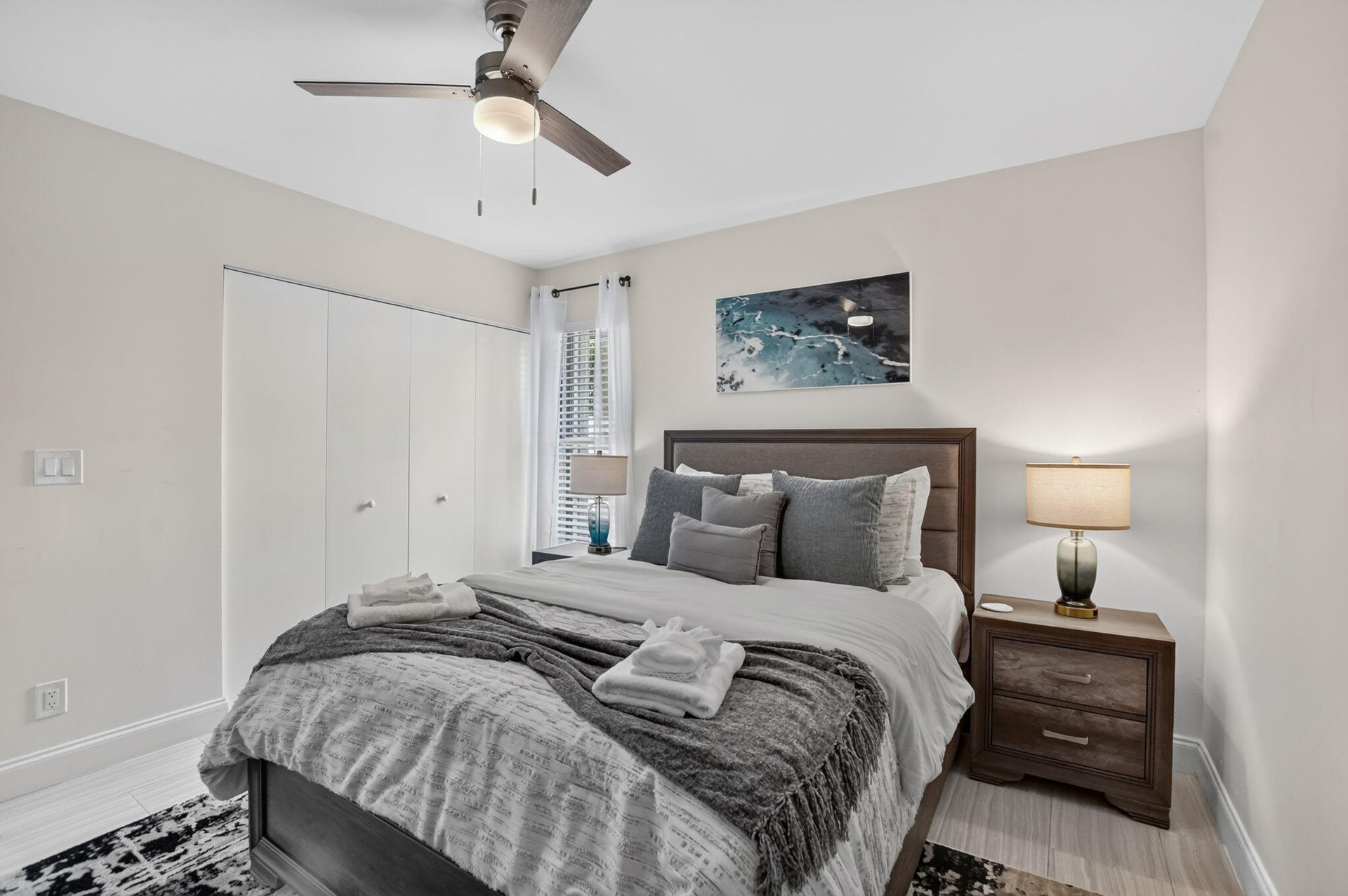 Light wood-finish flooring, a ceiling fan with integrated lighting, and white bi-fold closet doors