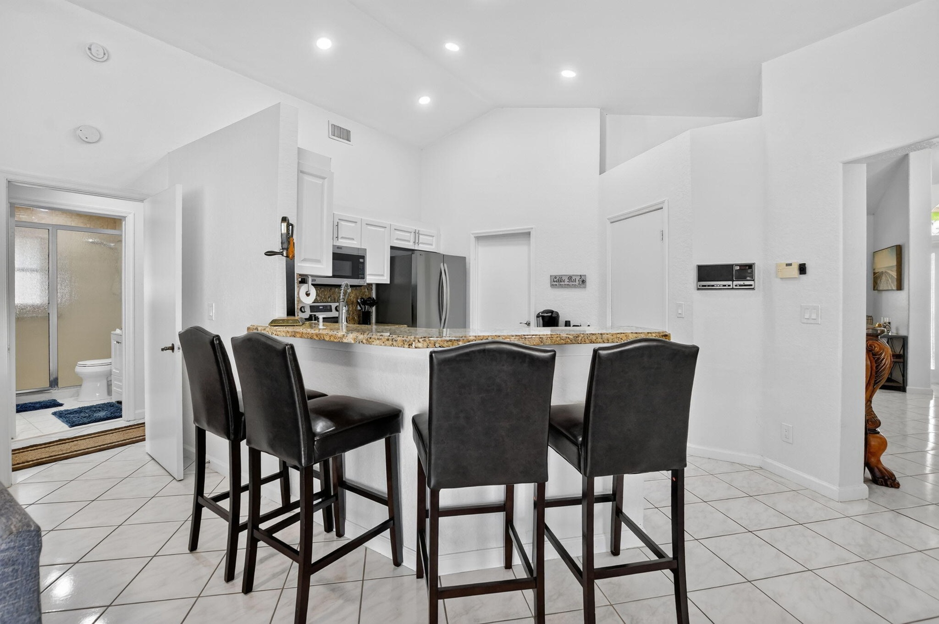 Kitchen with white cabinetry, stainless steel appliances, and a breakfast bar featuring a speckled countertop