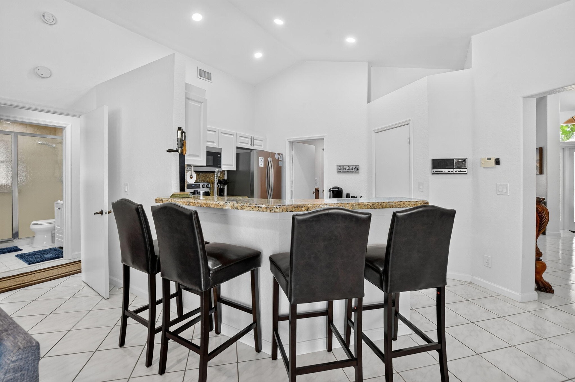 Kitchen featuring a breakfast bar with stone countertop, white cabinetry, stainless steel appliances, and recessed lighting