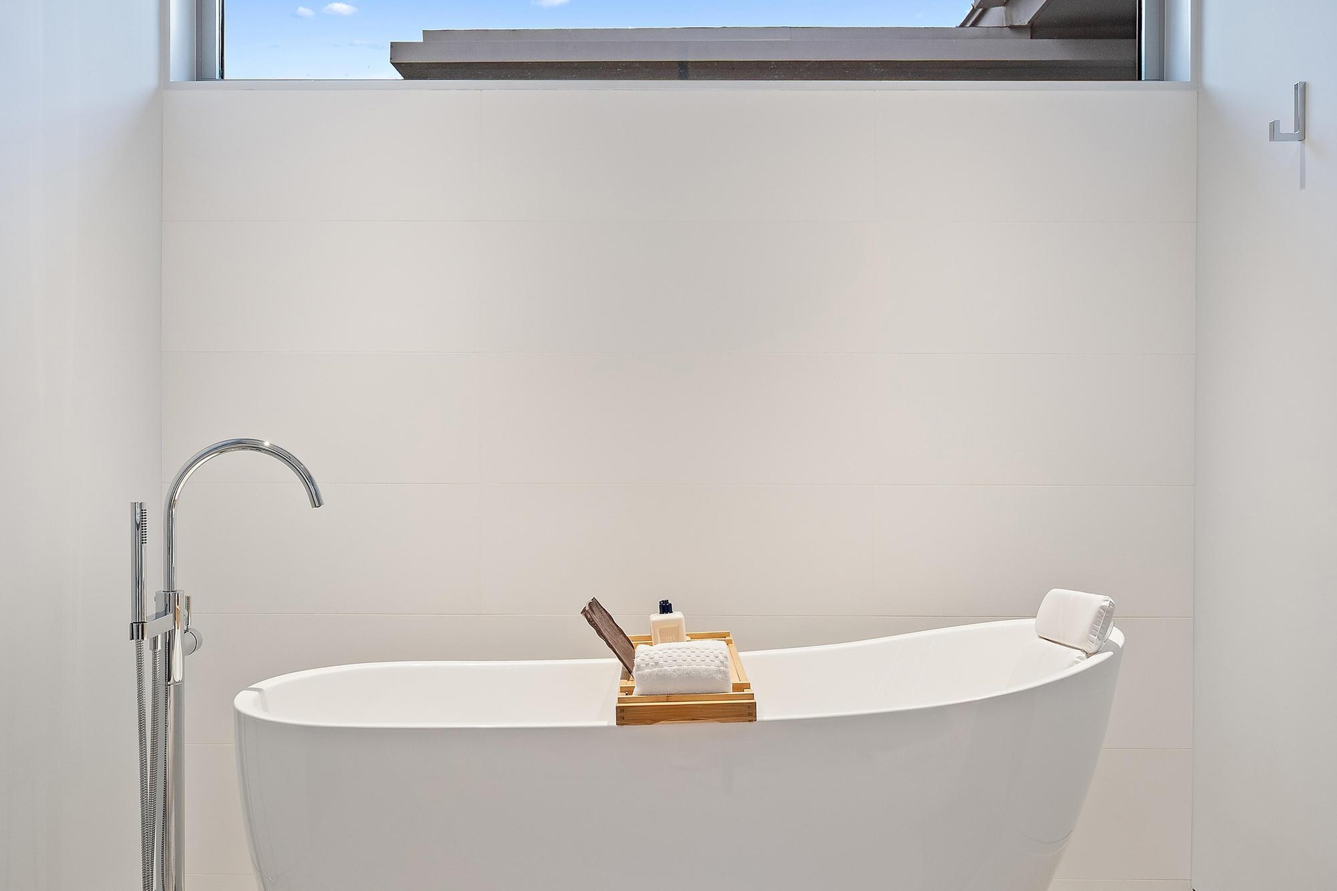 Modern spa-inspired soaking tub with curved silhouette and seamless white finish, paired with a contemporary floor-mounted freestanding tub filler fea