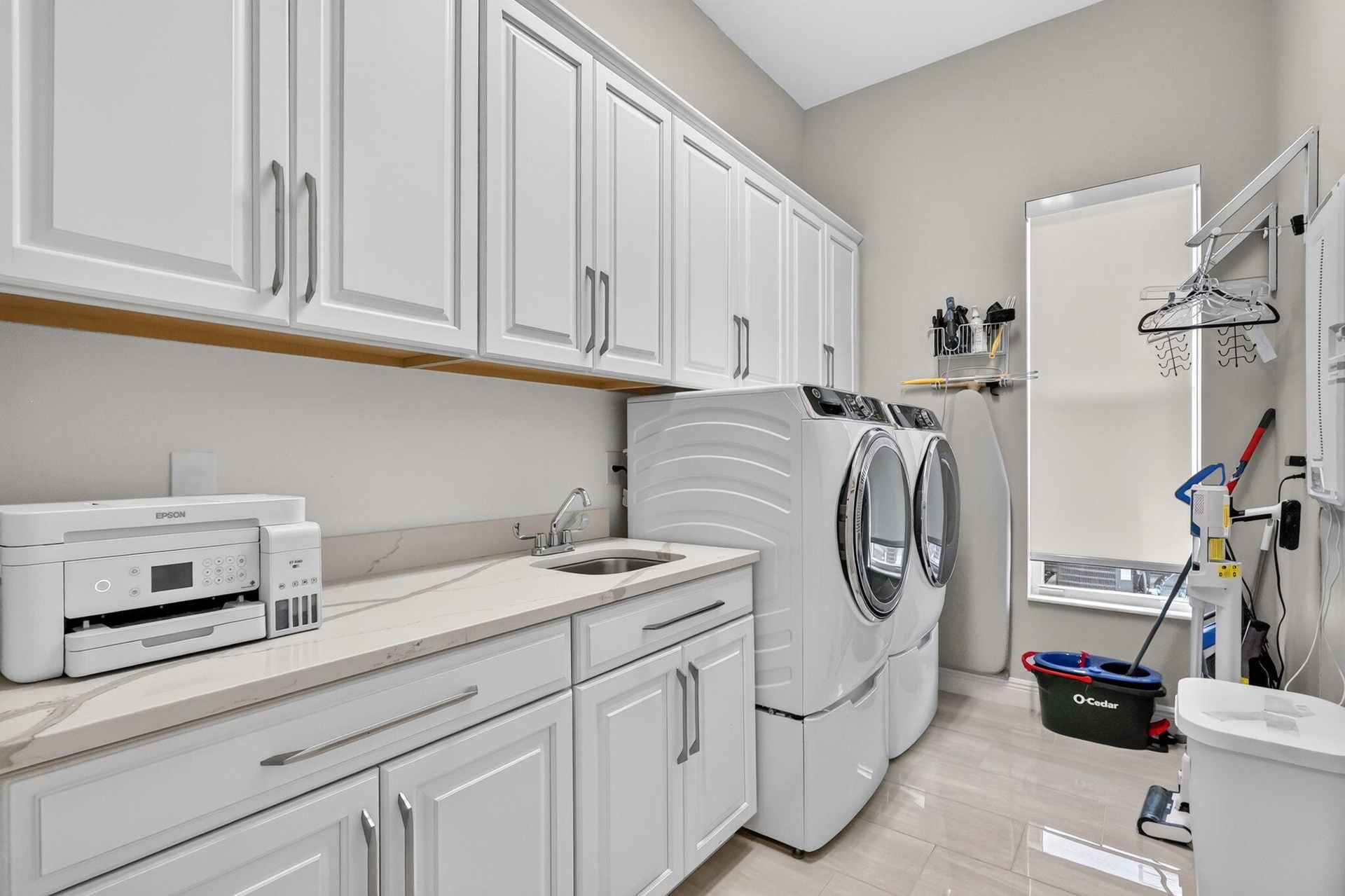 Large Laundry room with GE front loader washer and dryer with steam and lots of storage.