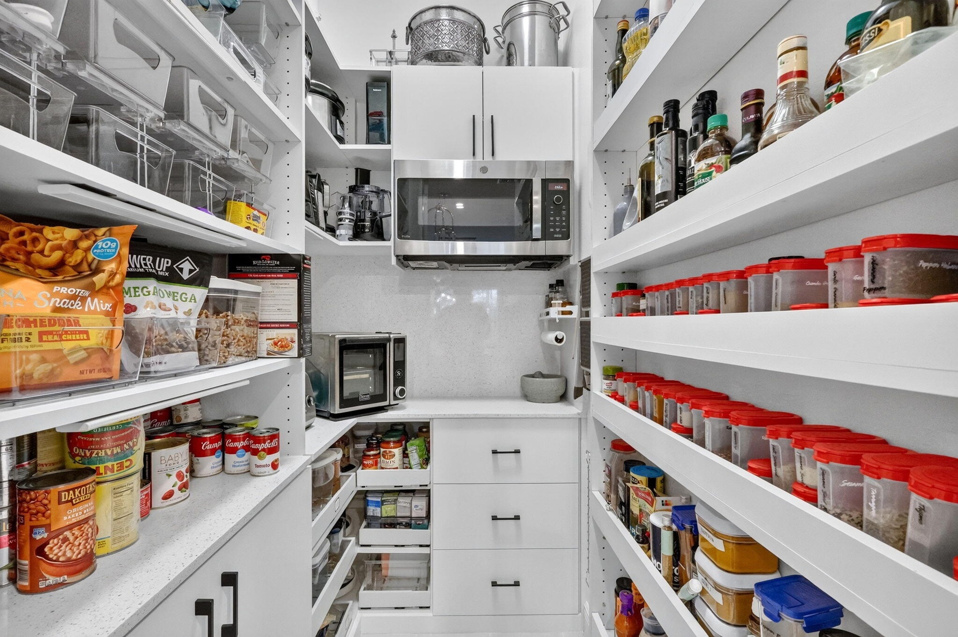 Custom Walk in Pantry with appliance cabinet, pull out shelves, custom spice rack, microwave, electric and quartz countertops.