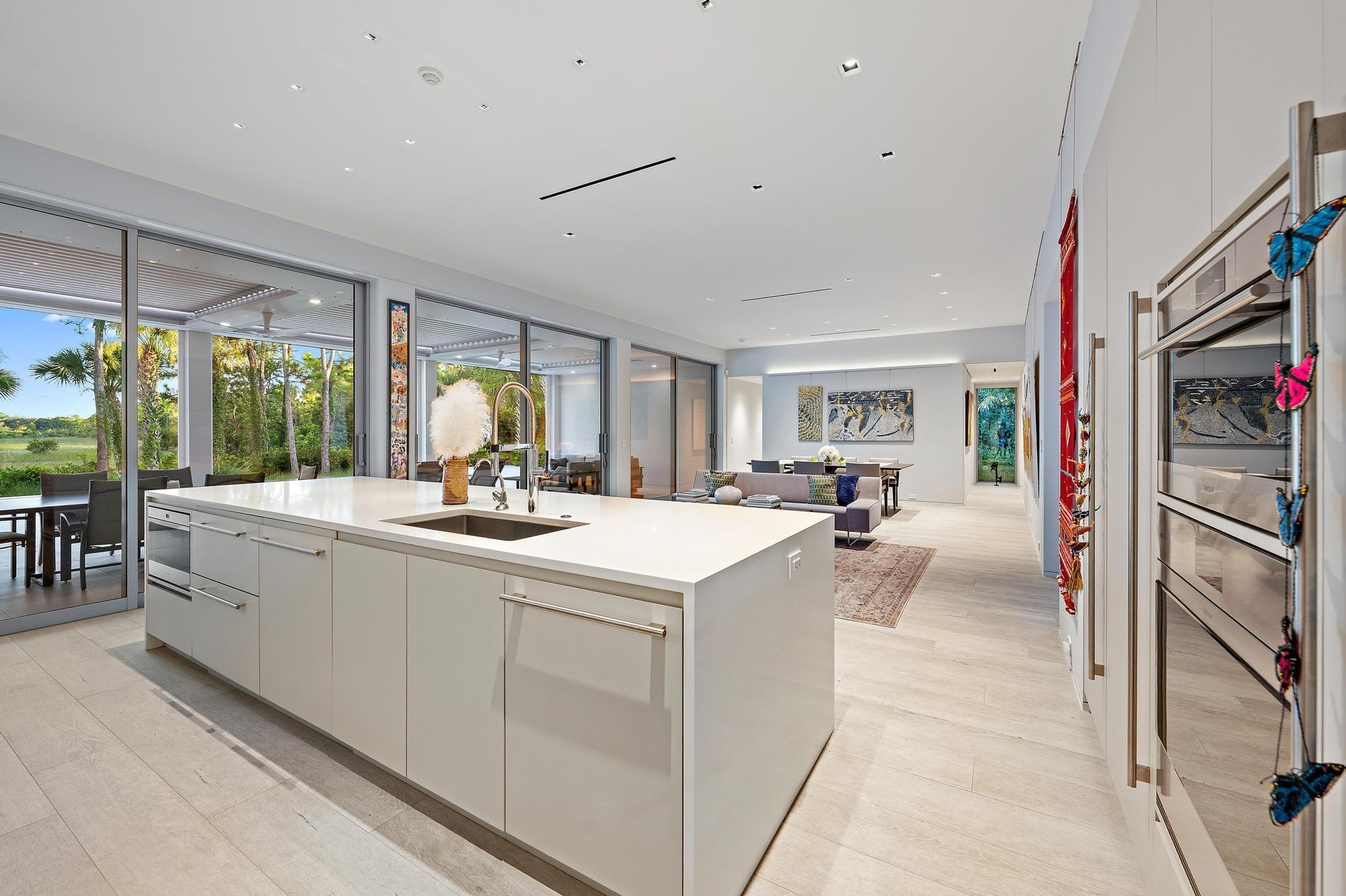 Contemporary kitchen anchored by a white cabinetry island with waterfall countertop, stainless steel appliances, and light wood-finish flooring
