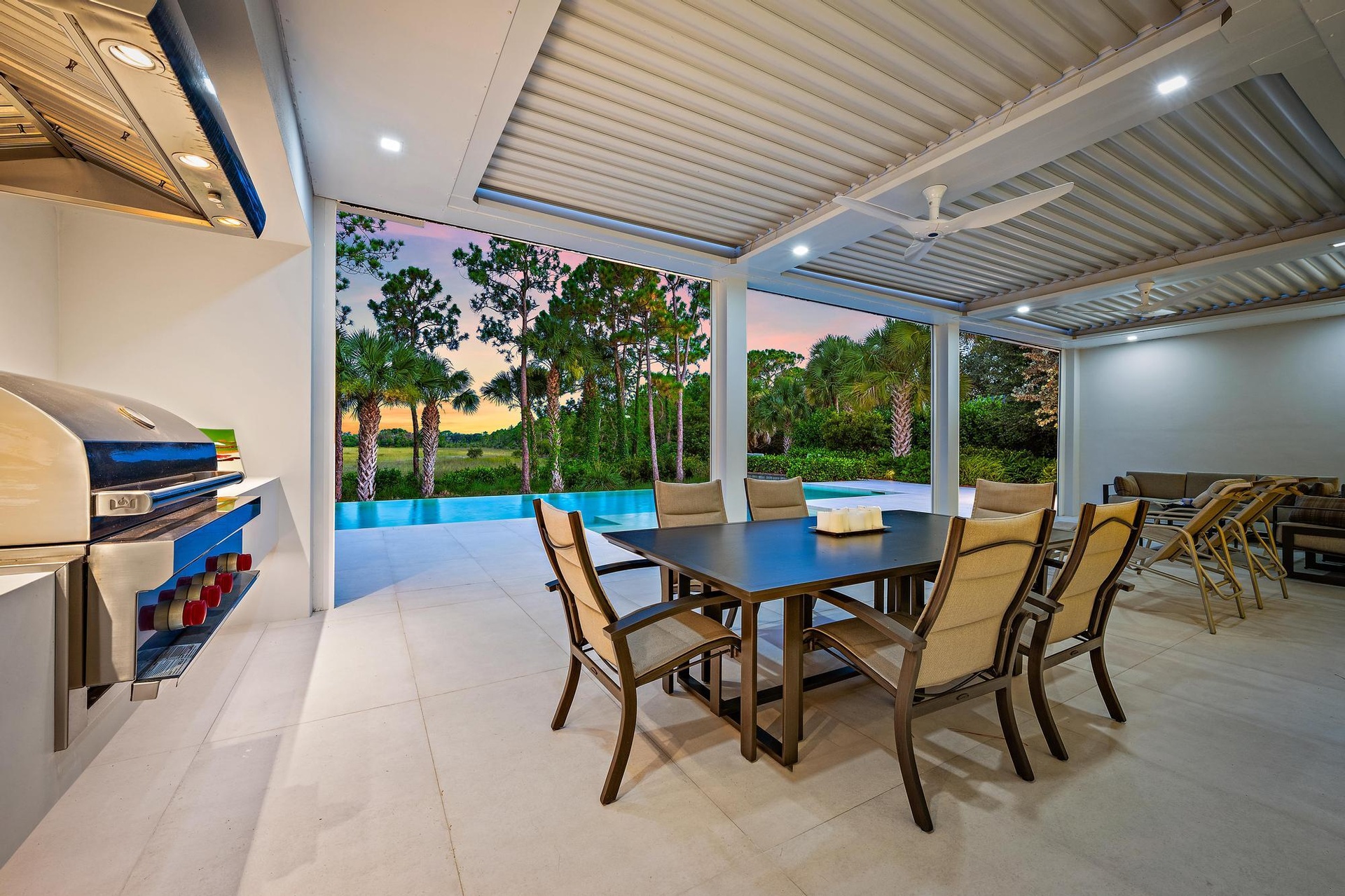 Sophisticated outdoor entertaining space featuring a covered patio with corrugated metal roof and integrated lighting, stone-finish flooring, and a wo