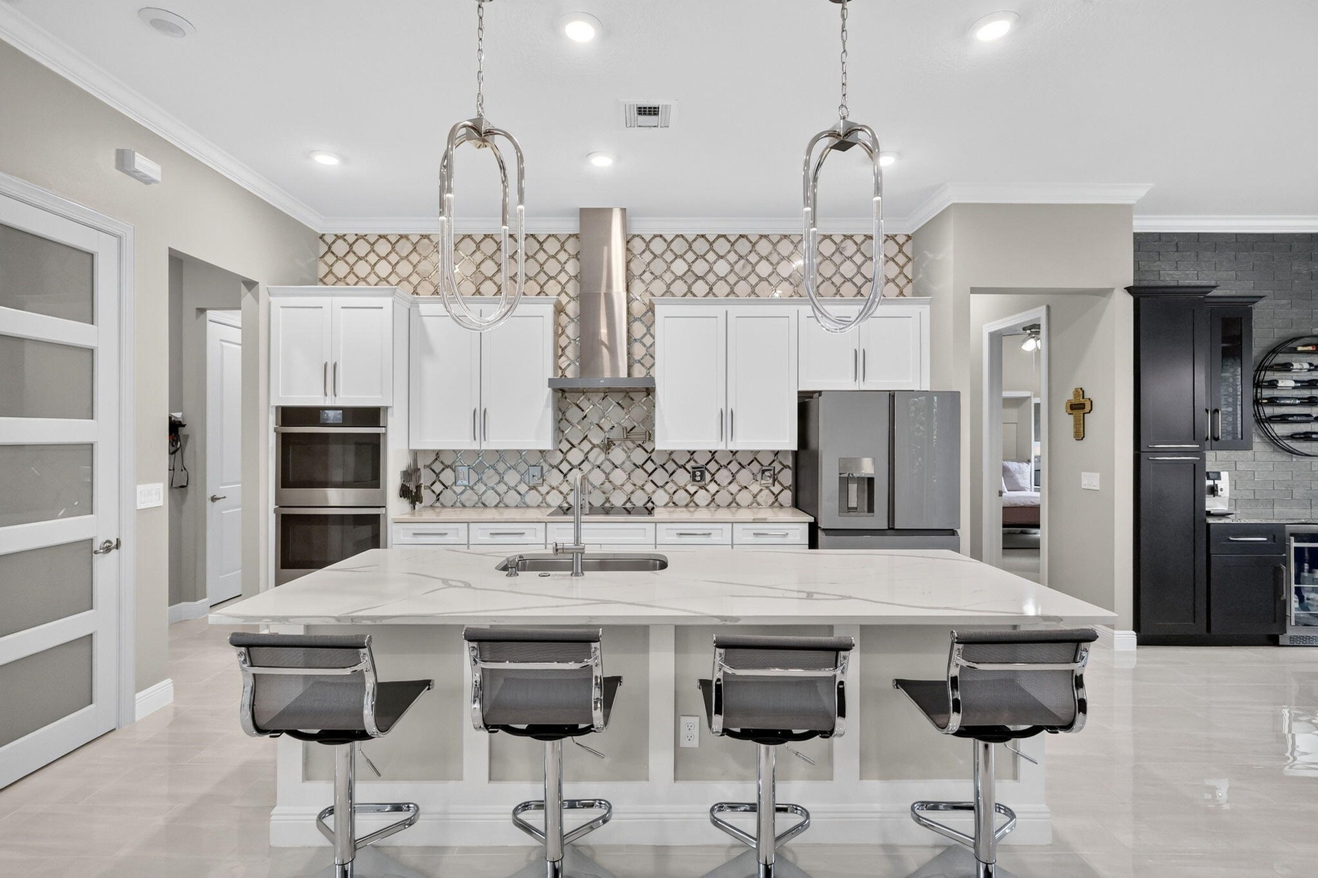 Custom Kitchen with island seating, designer pendant lighting, high end appliances, tile backsplash, double ovens.