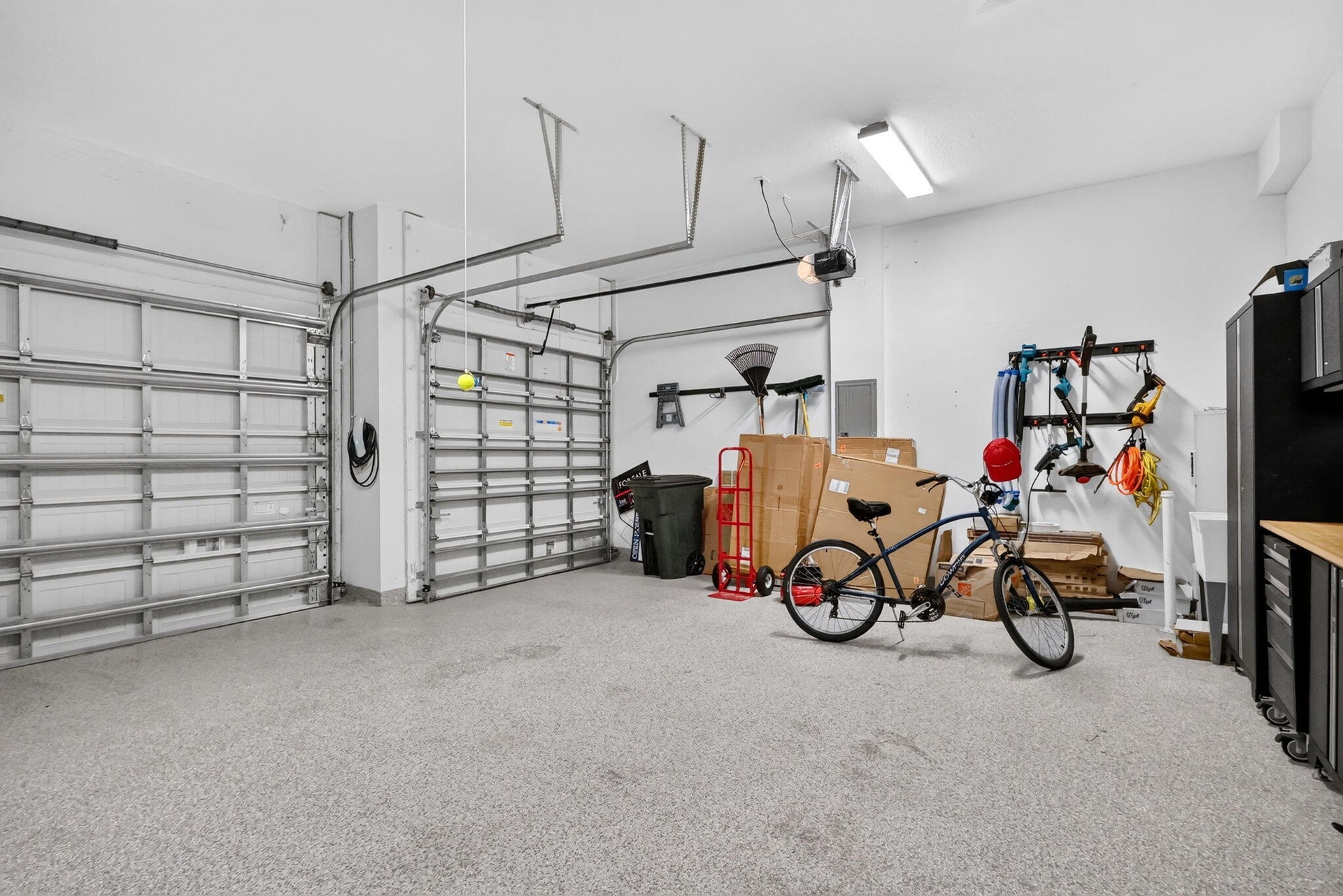 3 car garage with cabinetry, over head storage and finished floor.