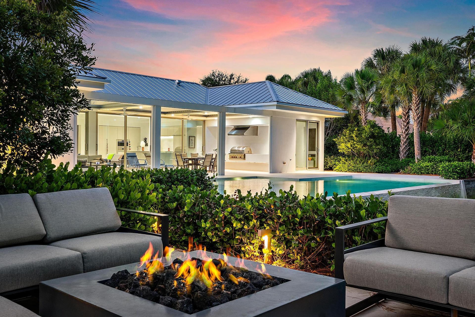 Modern residence with clean-lined architecture and metal roof, featuring expansive glass sliding doors and a covered porch
