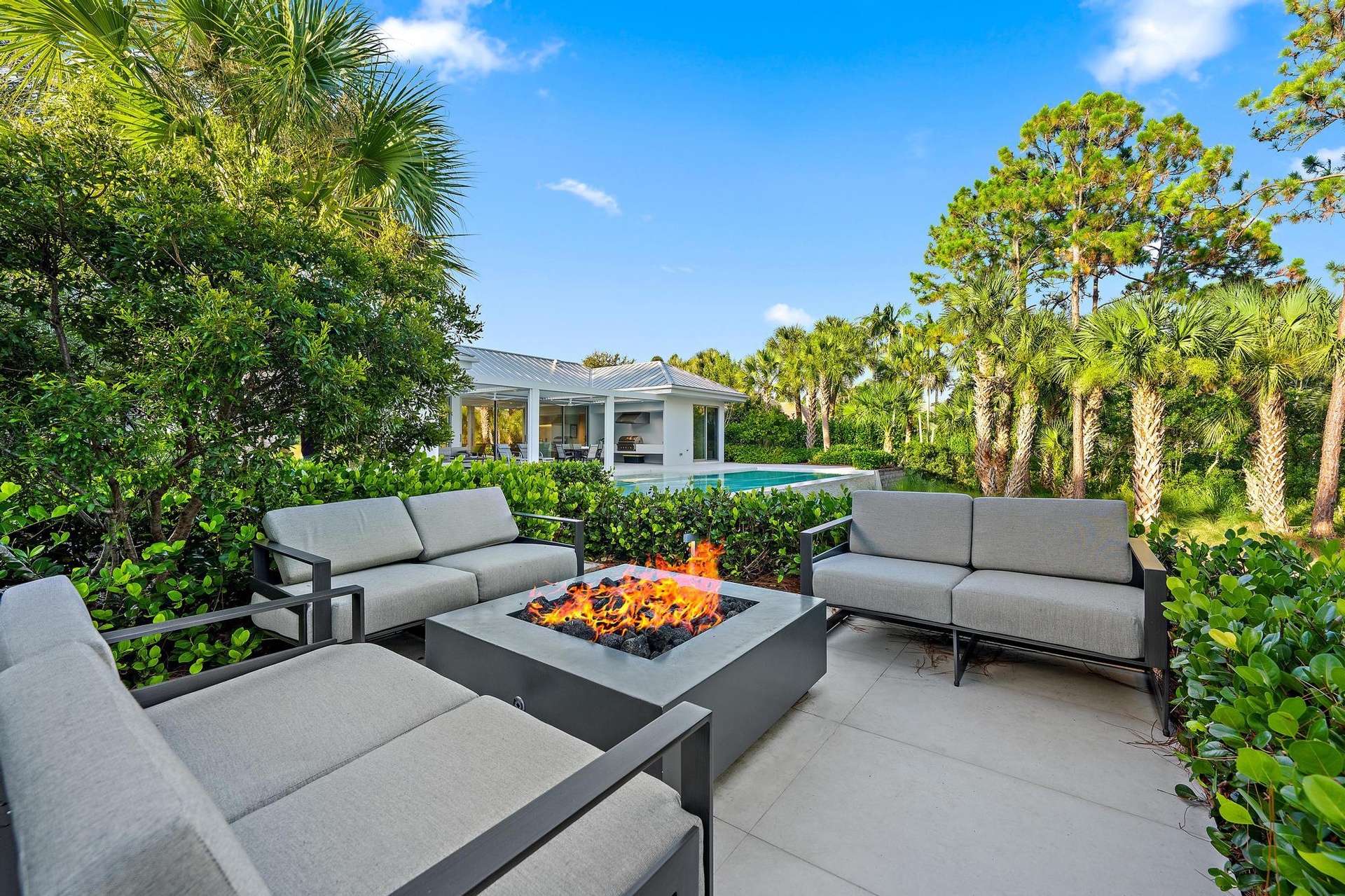 Expansive outdoor patio with a built-in fire pit, surrounded by lush landscaping and mature trees