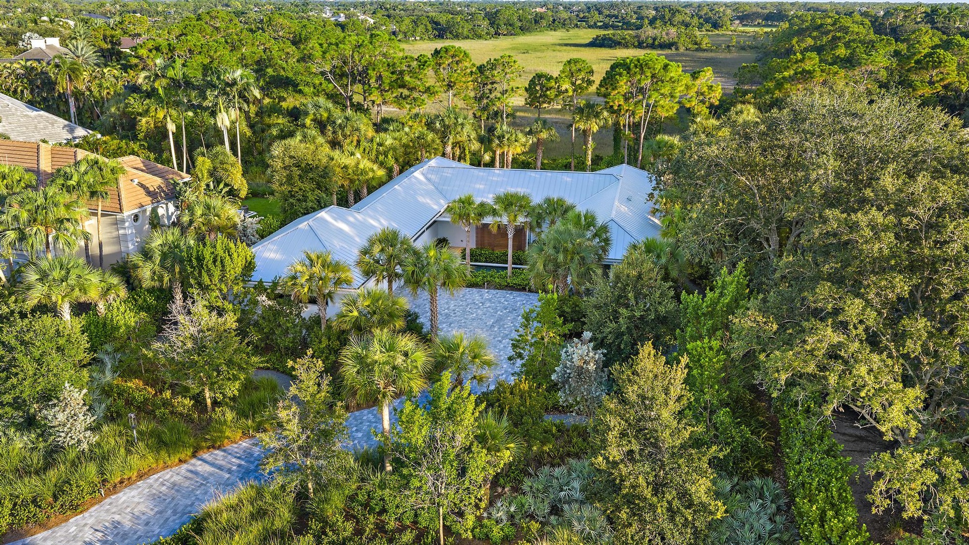 Expansive property featuring lush, mature landscaping and a metal roof