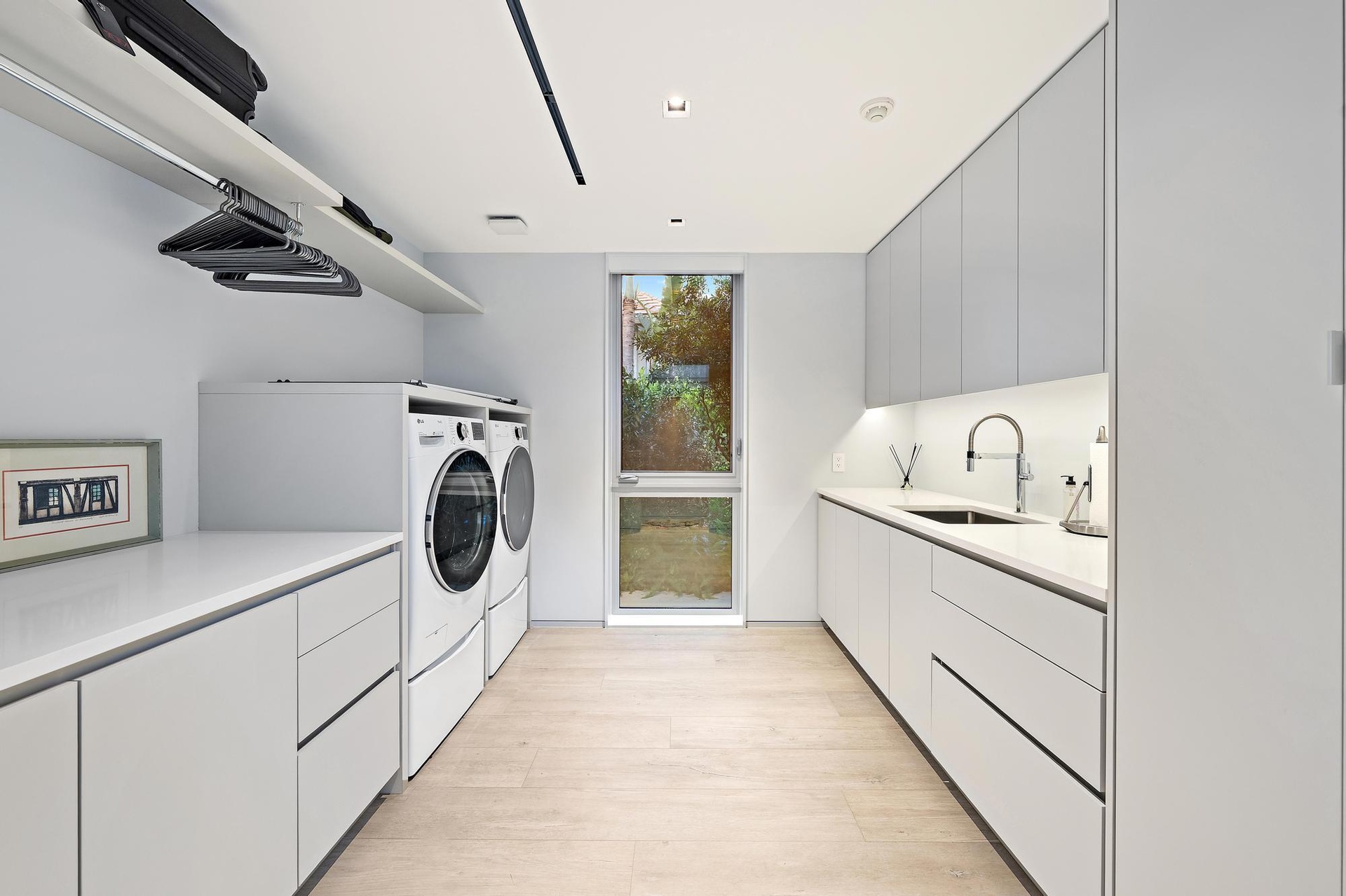 Integrated laundry appliances, extensive counter space, sleek cabinetry, recessed lighting, and wood-finish flooring