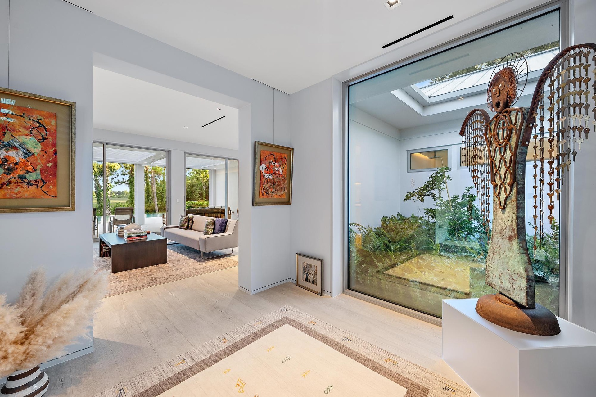 Bright, open interior showcasing light wood-finish flooring, recessed ceiling lighting, and large glass sliding doors framing landscape views