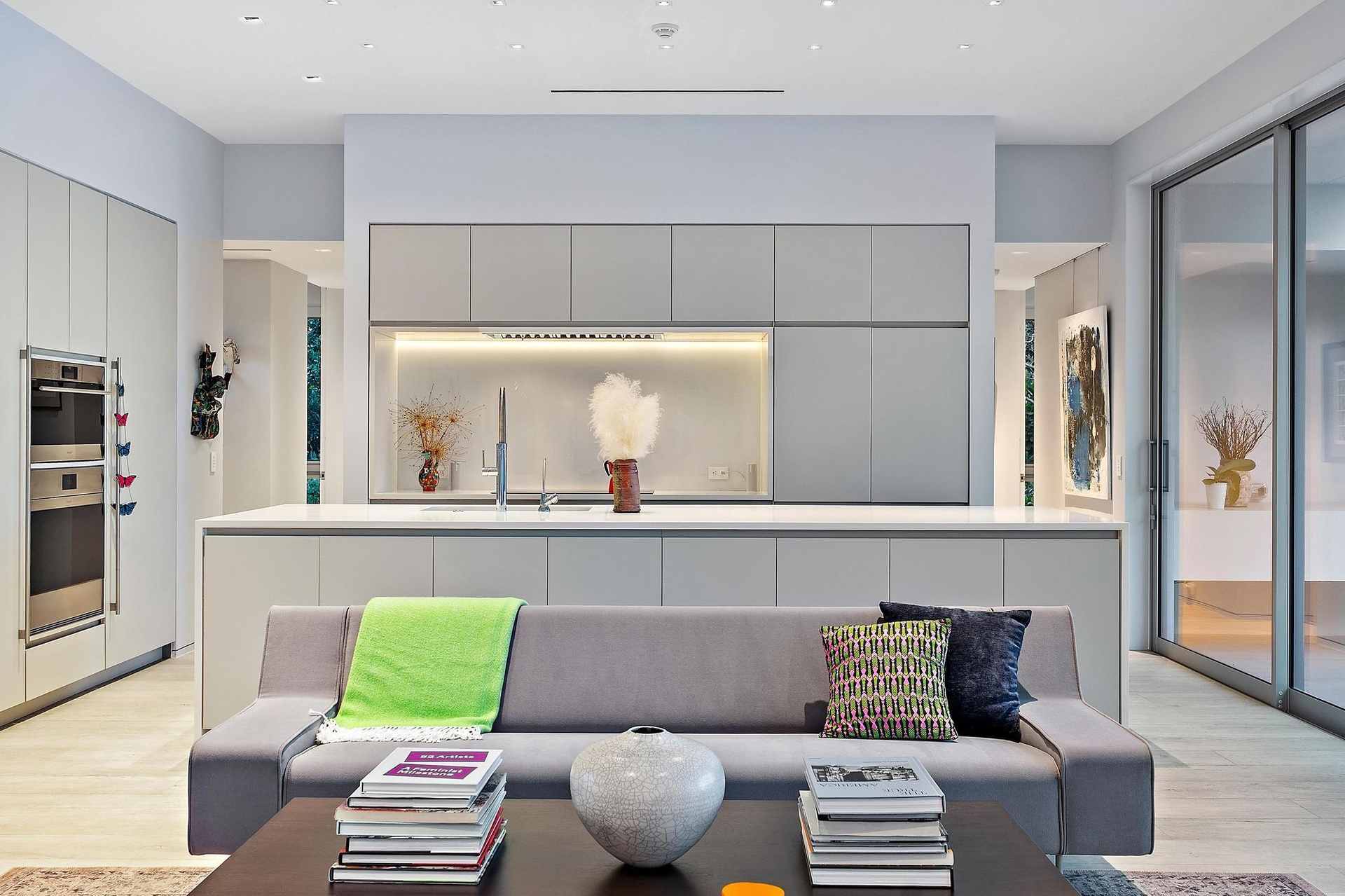 Contemporary kitchen with integrated appliances, extensive cabinetry, a large center island, under-cabinet lighting, and wood-finish flooring