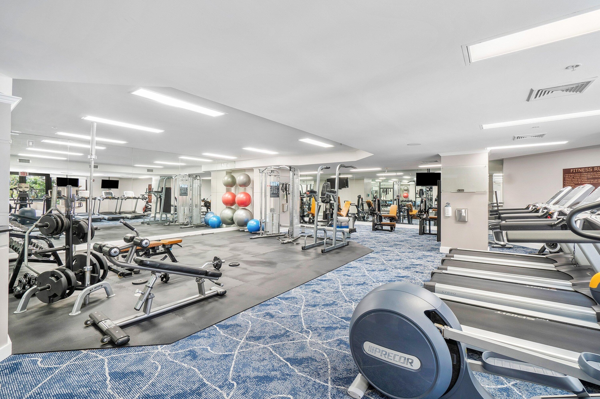 Fitness center featuring extensive cardio equipment, weight training machines, free weights, and mirrored walls