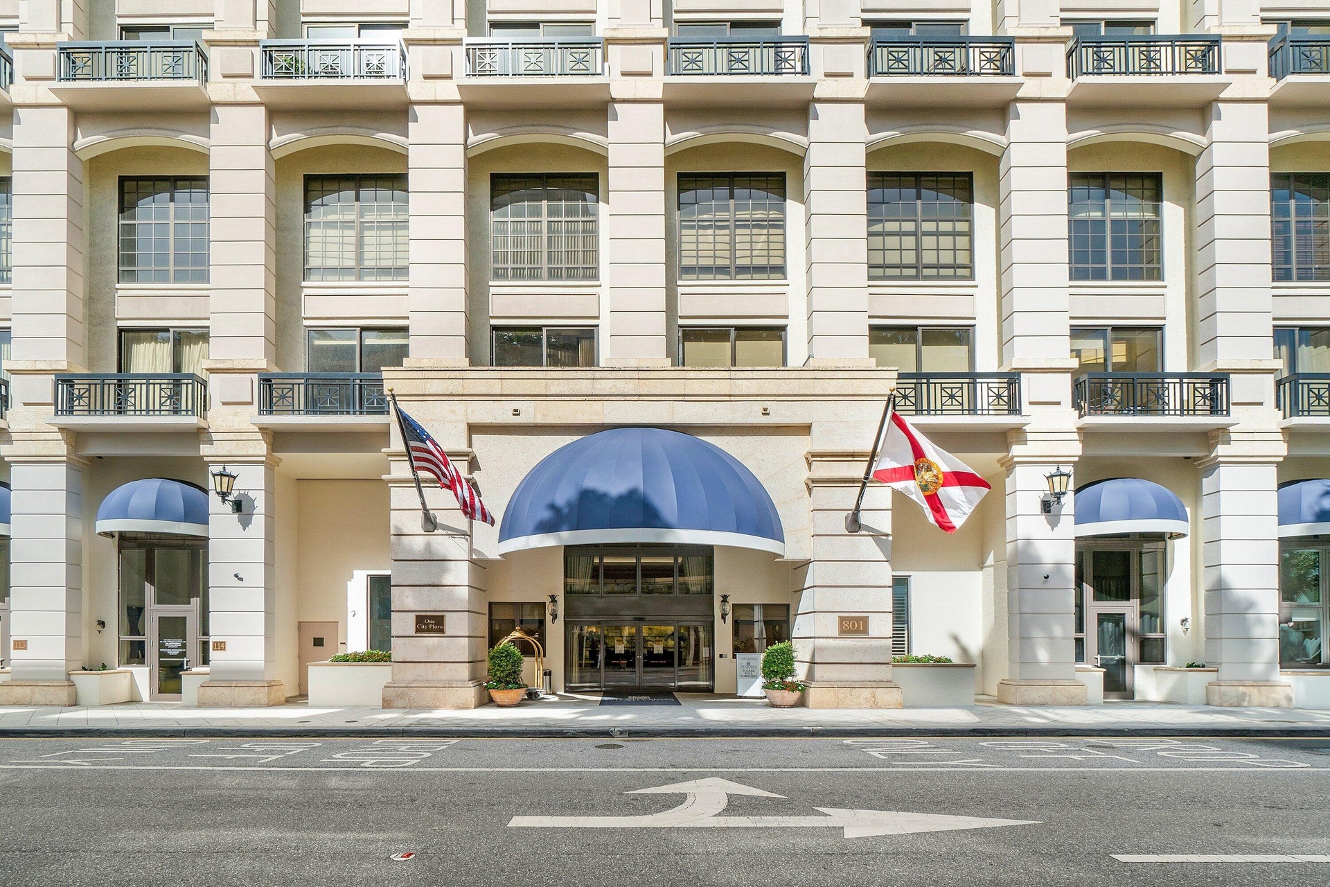 Multi-story facade featuring arched windows, Juliet balconies with wrought iron railings, and a grand entrance with a blue awning