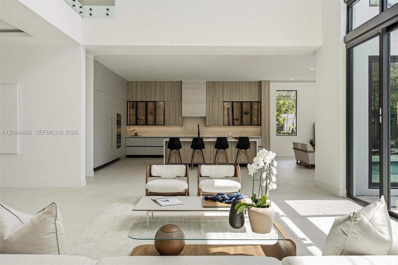 Double-height ceiling, glass-paneled staircase railing, built-in recessed lighting, recessed linear ceiling accents, and a wood-finish front door with
