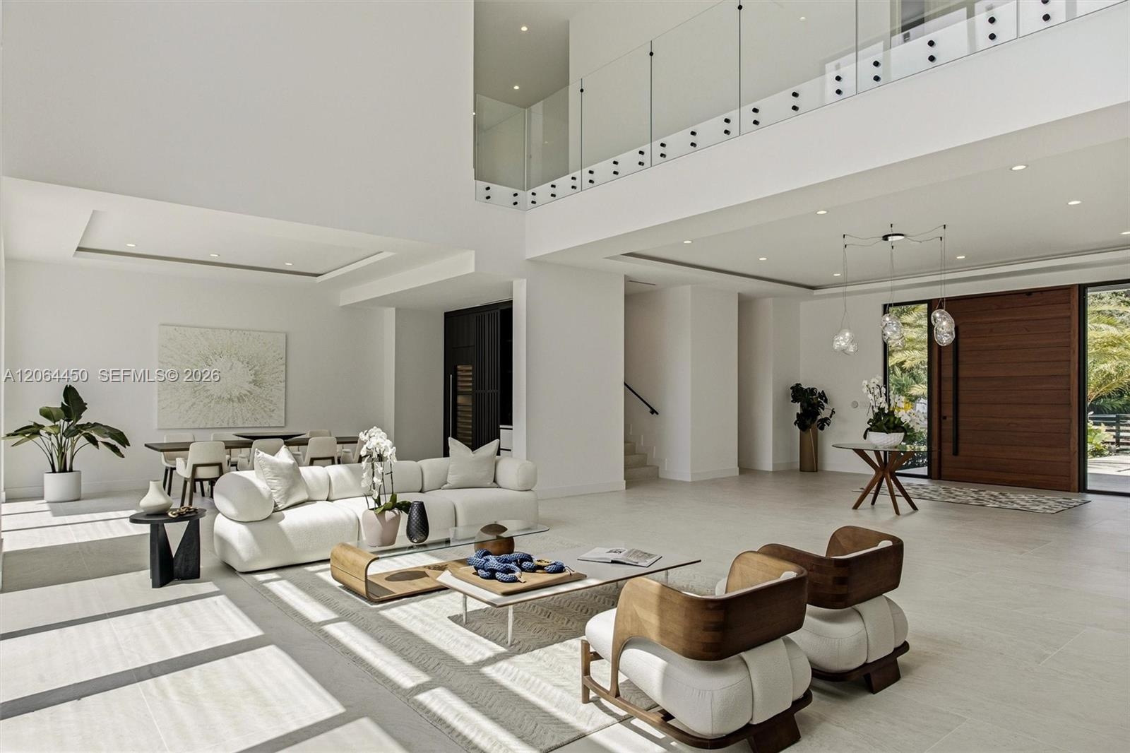 Great room with floor to ceiling windows framing the pool and tropical landscaping