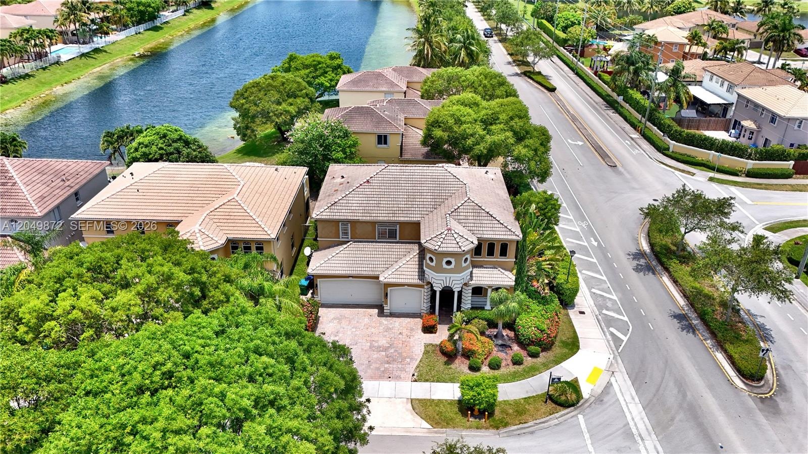 Stucco exterior featuring a two-story turret, arched entryway, decorative molding, concrete driveway, and mature landscaping