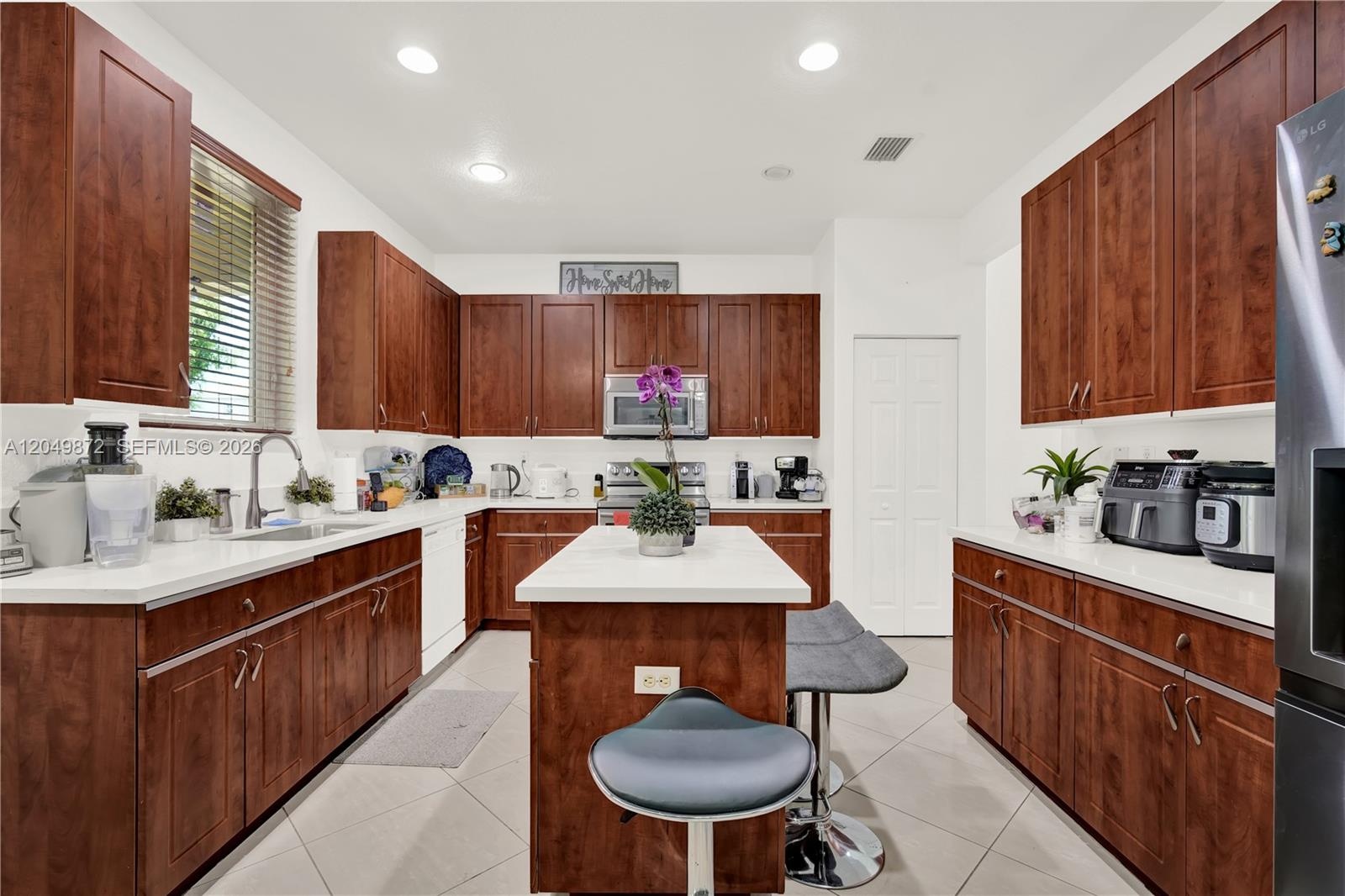 Bathroom featuring a vanity with an integrated countertop, four-light vanity fixture, wall-to-wall mirror, and a window with a horizontal blind