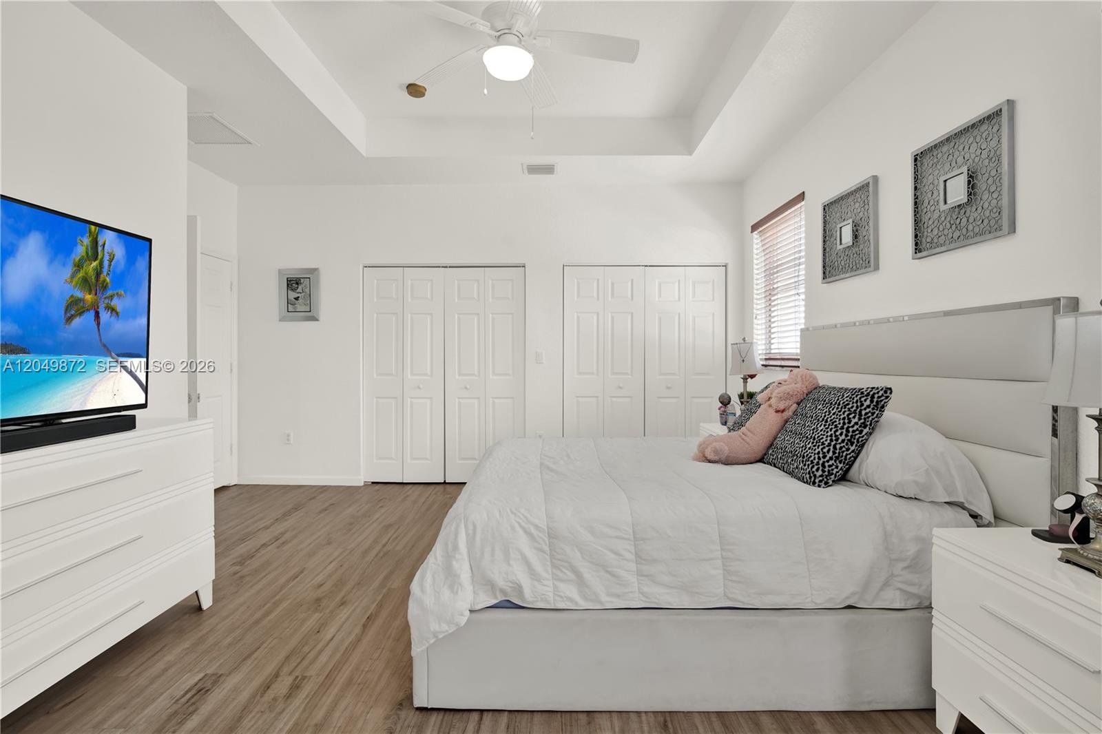 Room featuring wood-finish flooring, vaulted ceiling, arched window with a transom, and bifold closet doors