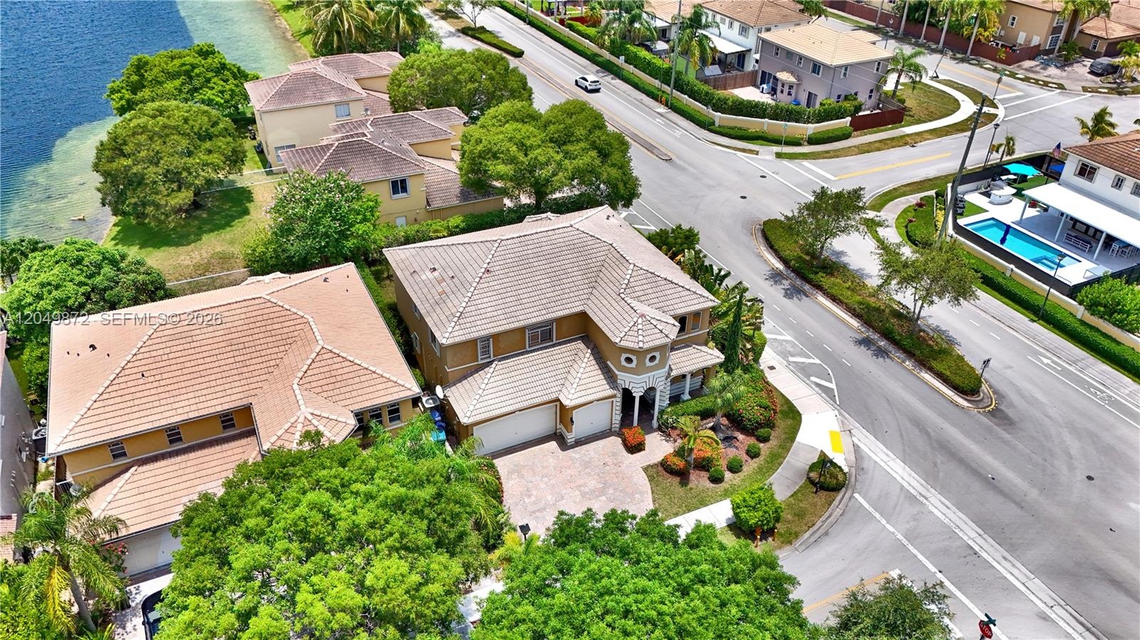 Covered rear patio featuring stucco columns, tile flooring, and double glass doors, complemented by a fenced backyard with established landscaping