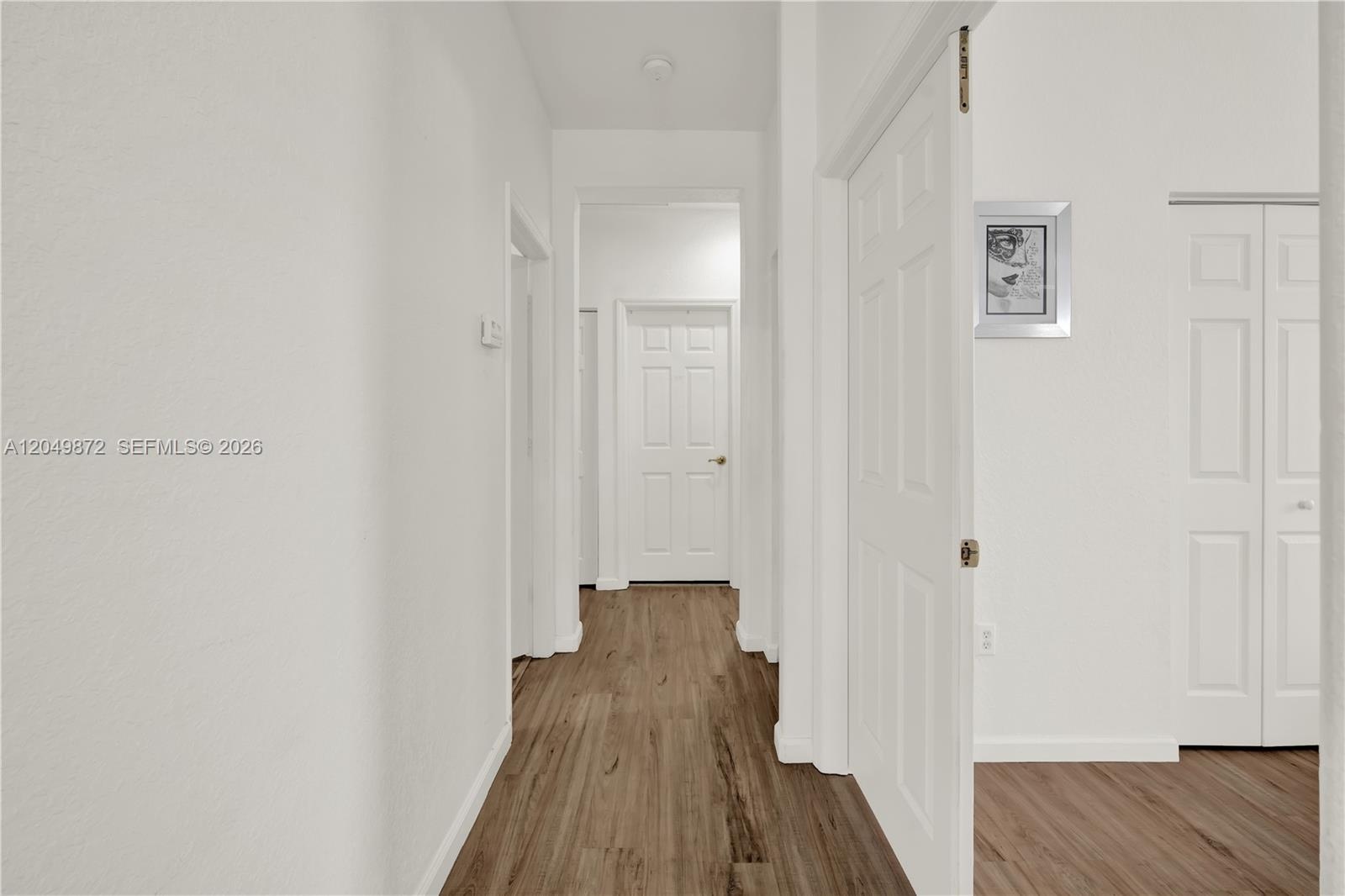 Hallway featuring wood-finish flooring, a built-in recessed wall niche, and a wooden handrail with vertical balusters