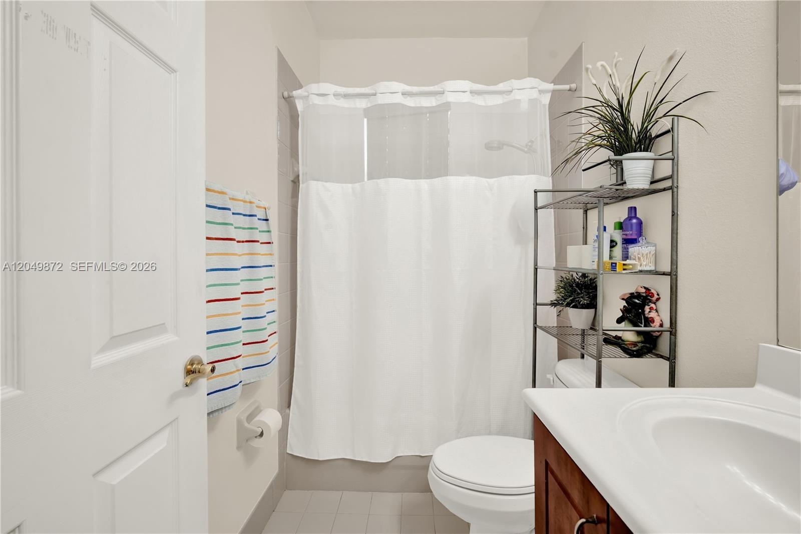 Bathroom featuring a wood-finish vanity with a solid-surface countertop, an expansive wall-mounted mirror, a tiled shower enclosure, and a built-in so