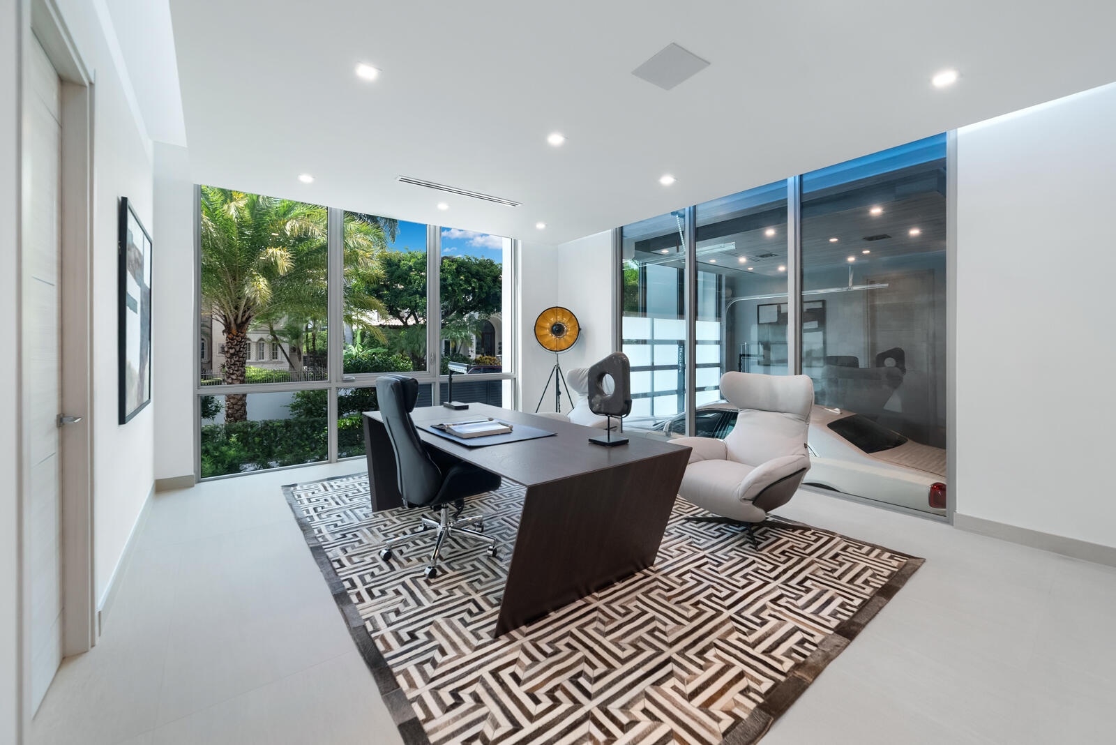 Exceptional executive office featuring a glass wall overlooking the climate-controlled automobile gallery, located within the three-car garage on the 