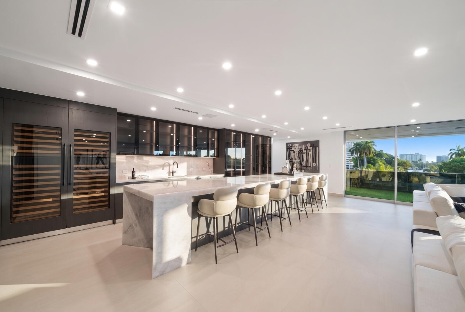 Showpiece 20-foot illuminated onyx bar featuring generous seating, custom smoked-glass cabinetry, dual wine storage, and sweeping skyline views.