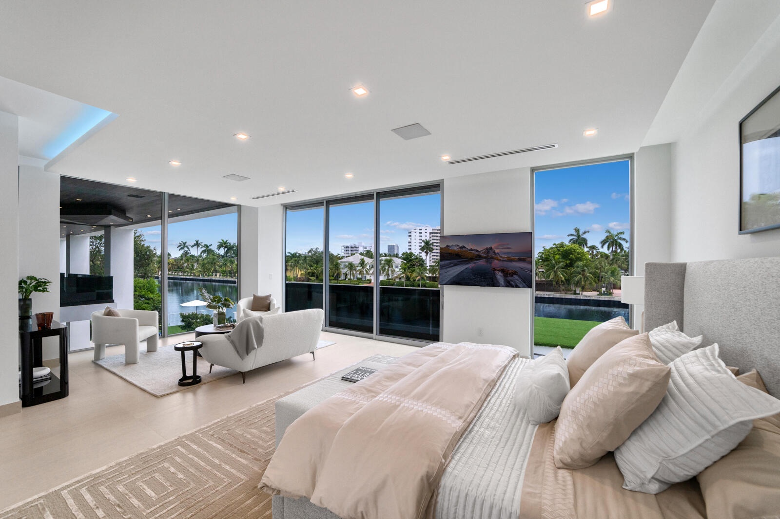 Private primary retreat with floor-to-ceiling glass framing sweeping canal and skyline views from the bedroom and adjoining sitting area.