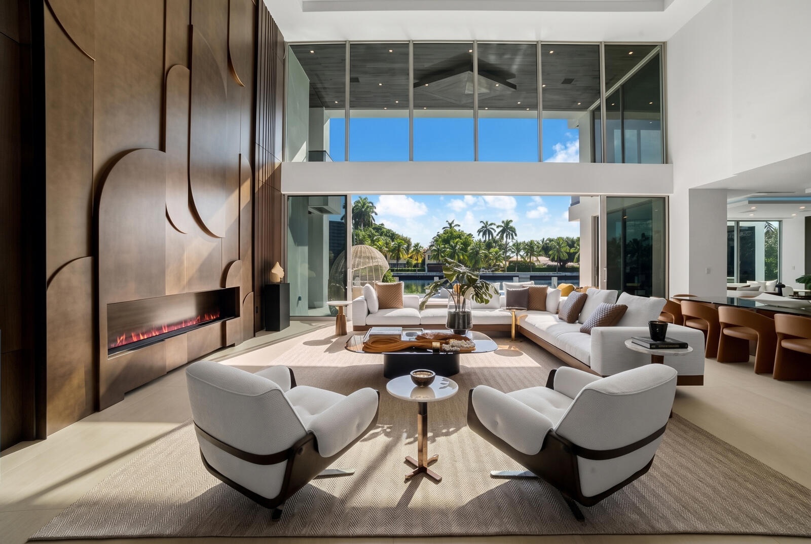 Sun-filled waterfront great room featuring floor-to-ceiling glass, refined designer furnishings, and seamless views of the pool and canal.