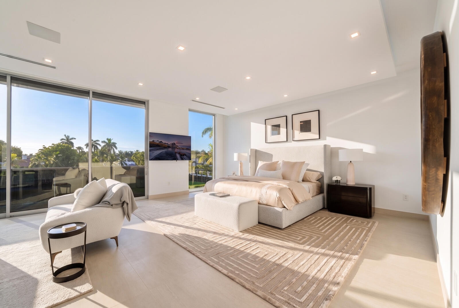 Serene second-floor primary bedroom featuring a private waterfront sitting area, walls of glass, and direct access to the covered terrace.