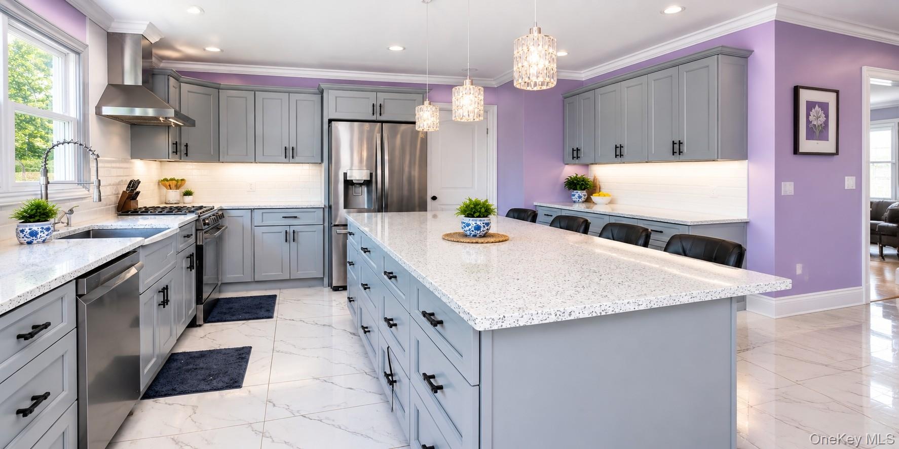 Kitchen featuring stainless steel appliances, an expansive island with seating, pendant lighting fixtures, light-toned countertops.