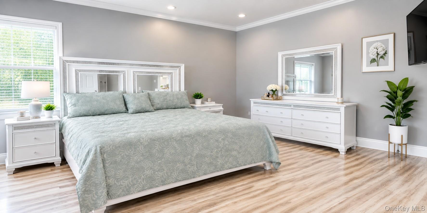Spacious Bedroom with a new full bath. Neutral wall color, crown molding, new finished flooring, recessed lighting, and a big window