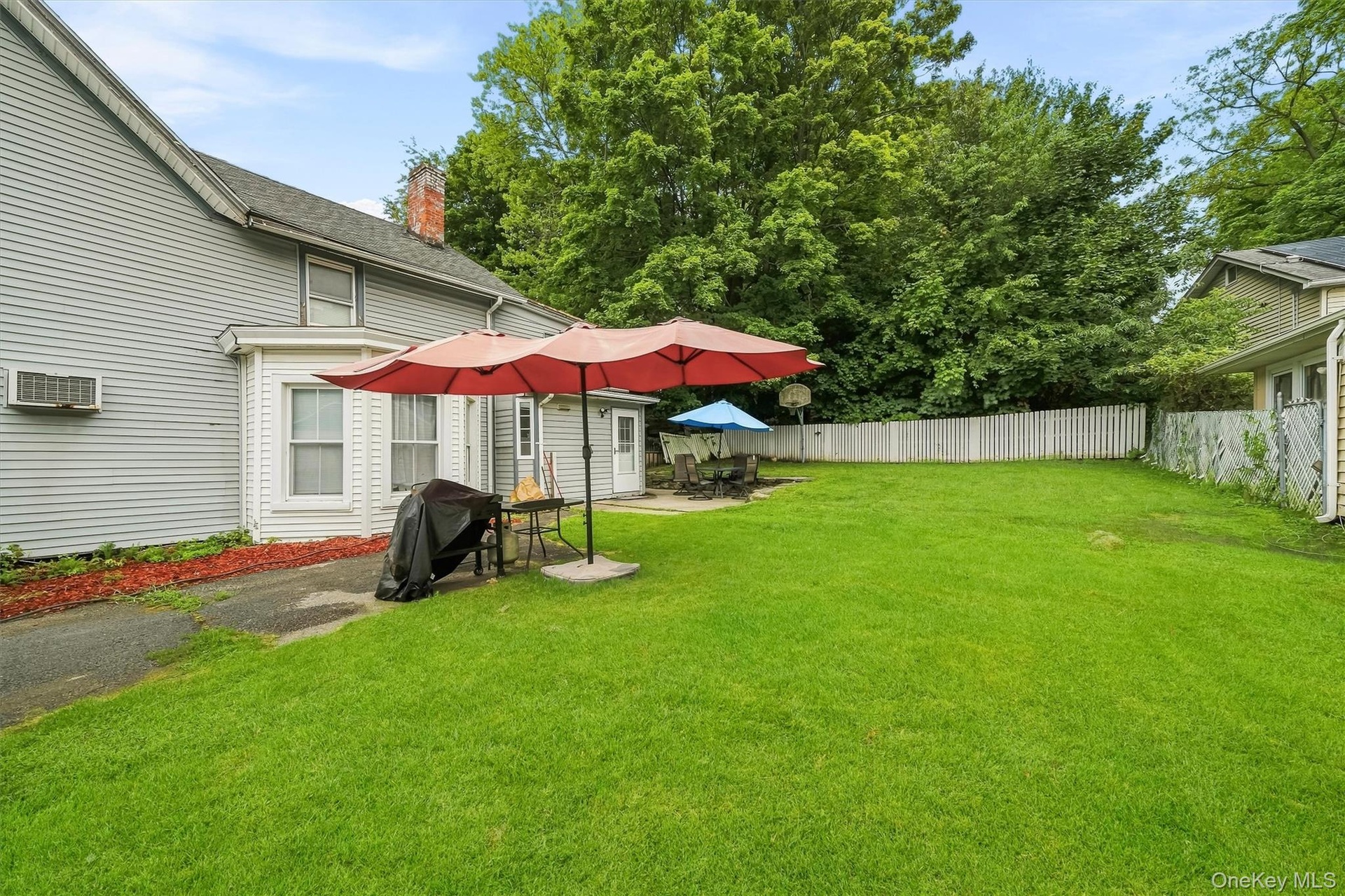 Spacious fenced backyard with multiple outdoor seating areas.