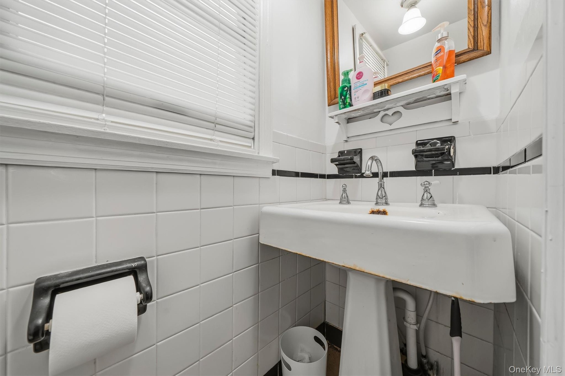 MAIN HOUSE - Main-level half bathroom with a pedestal sink and tiled walls.