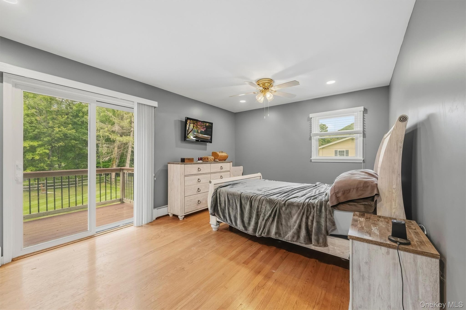 Sliding glass door leading to an outdoor deck, recessed lighting, wood-finish flooring, and a ceiling fan with integrated lighting