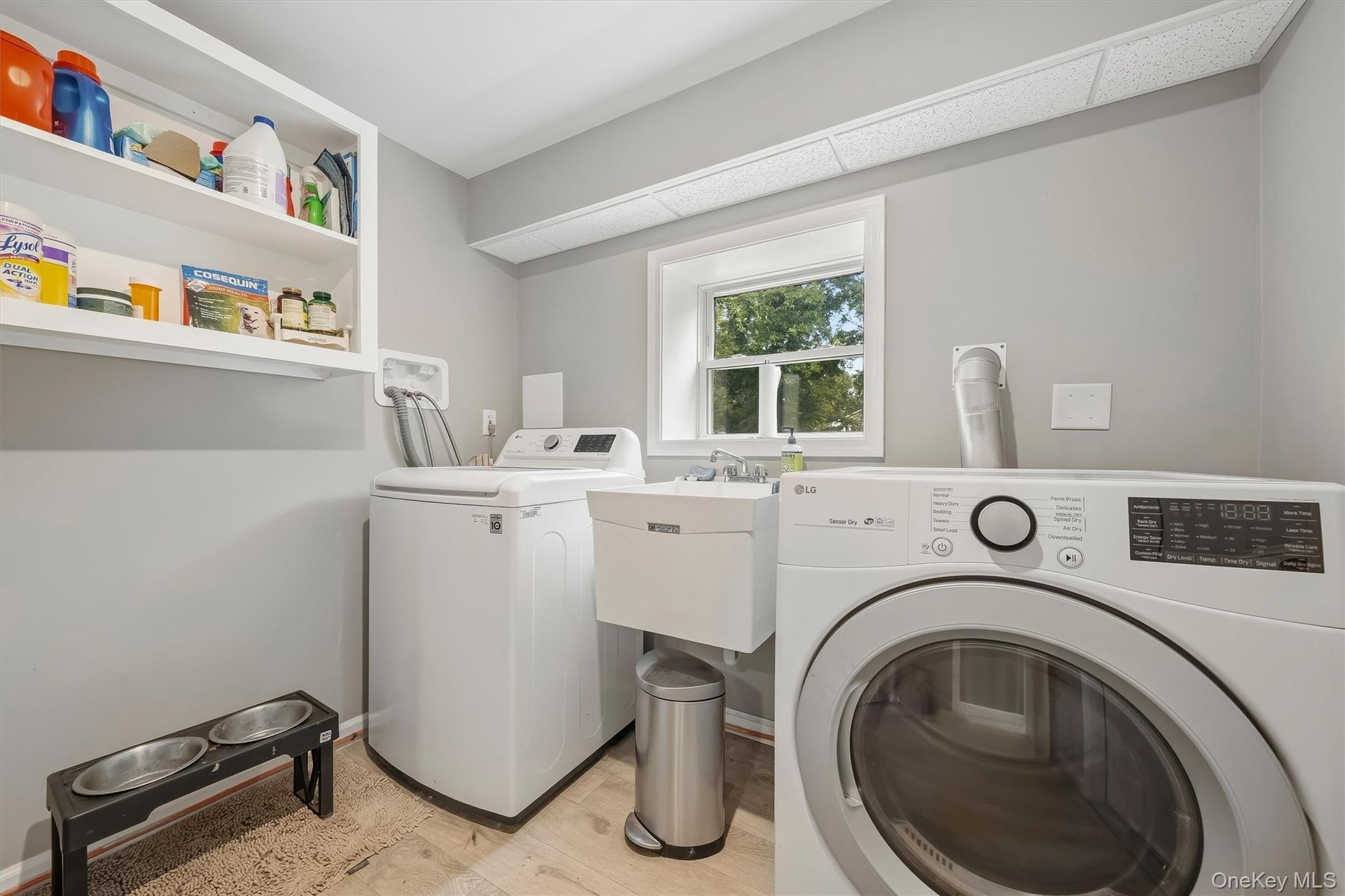 Laundry area featuring a utility sink, open shelving, and a window