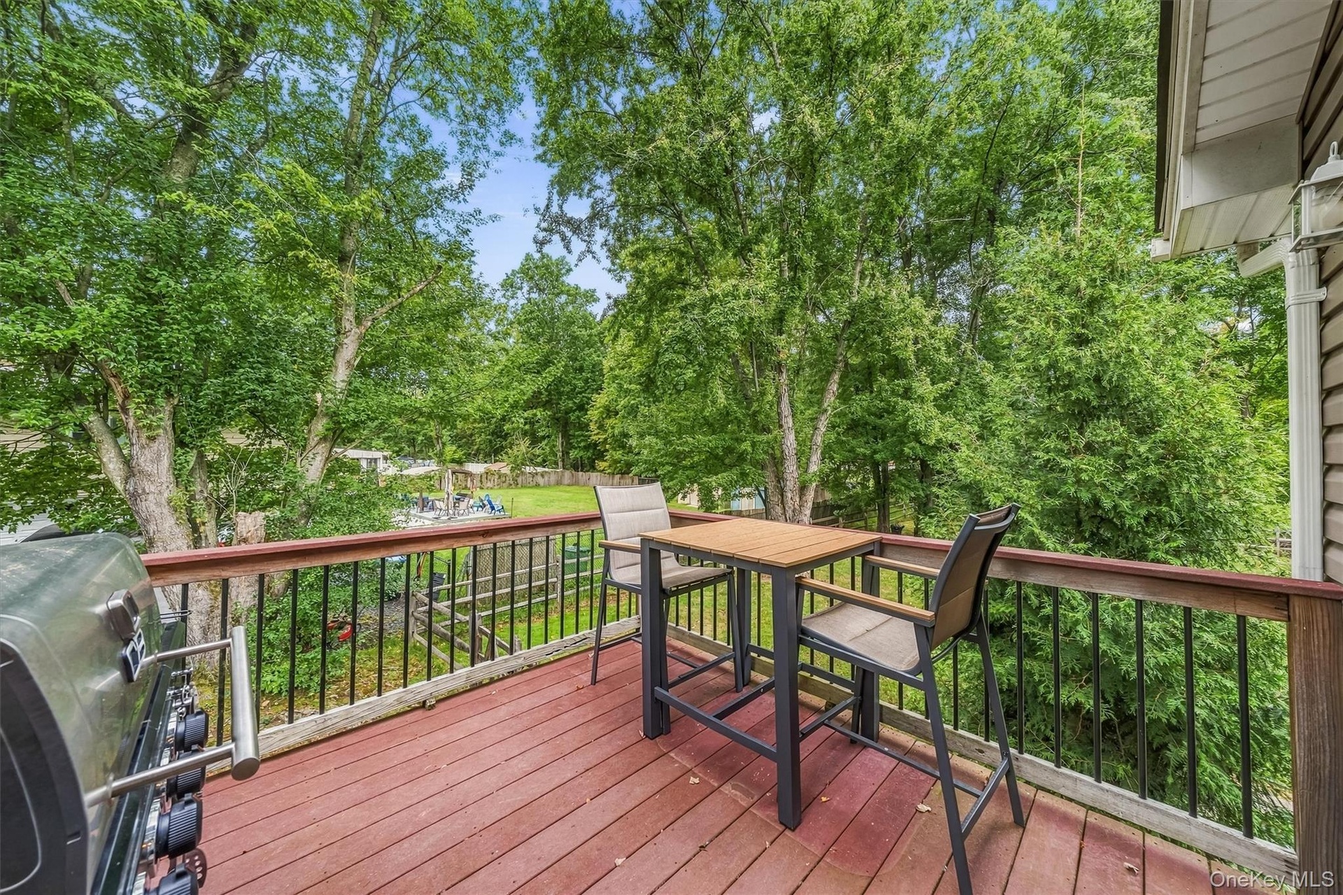 Expansive outdoor deck with red-stained wood flooring and black metal railings