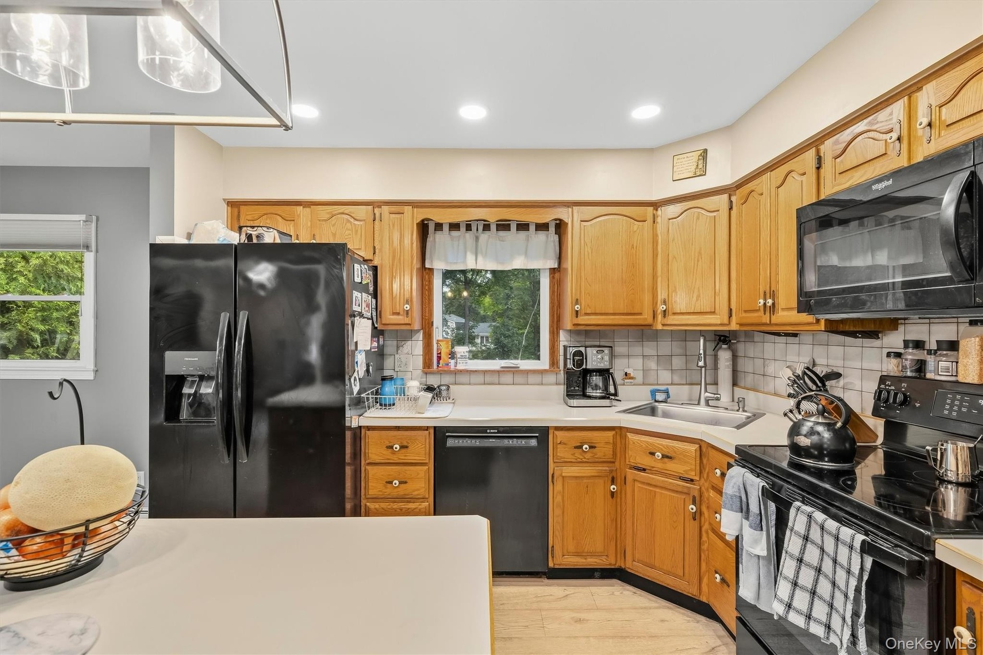 Kitchen featuring wood-finish cabinetry, black appliances, recessed lighting, and a tile backsplash