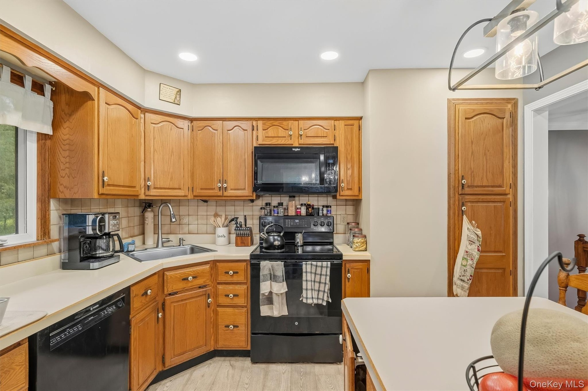 Kitchen featuring wood cabinetry, black appliances, a tile backsplash, and recessed lighting