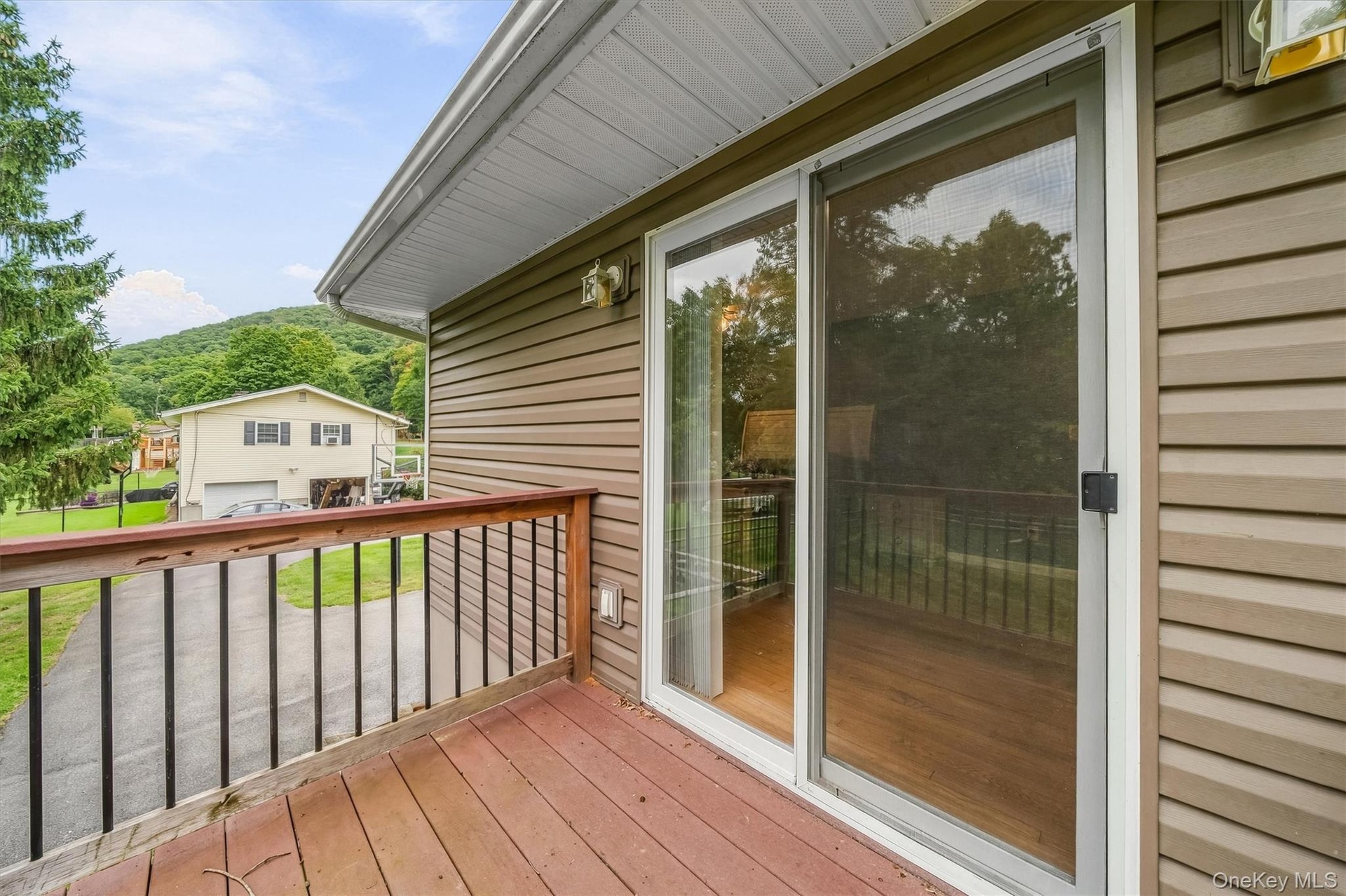 Exterior decking with wood railings, sliding glass door, and vinyl siding