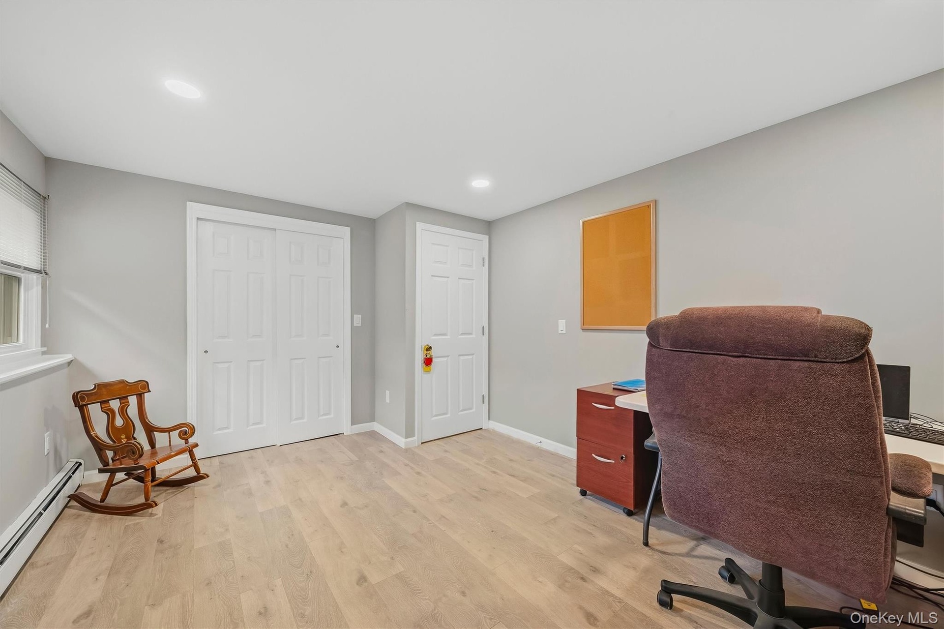 Recessed lighting, wood-finish flooring, two panel doors, window with roller shade, and light gray wall paint
