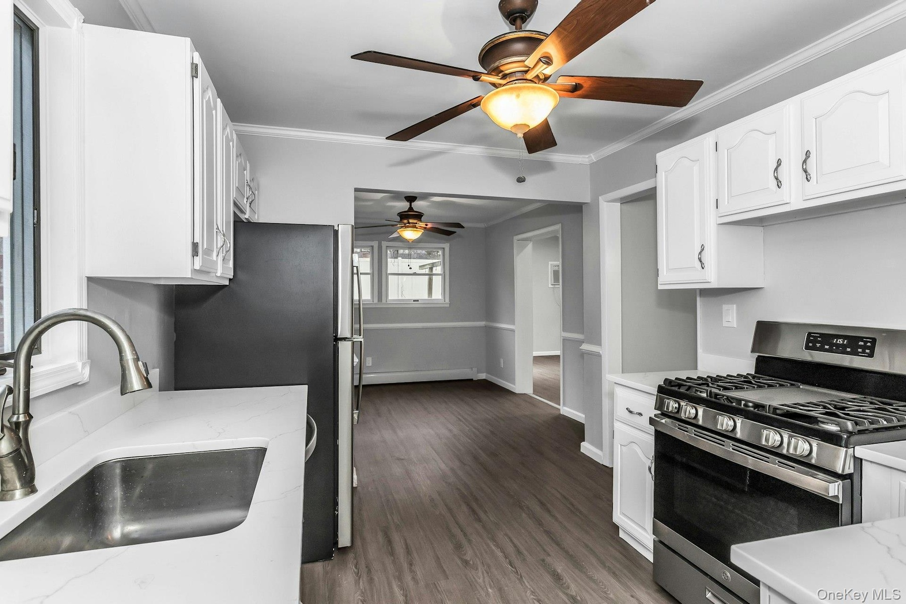 Kitchen featuring white cabinetry, light countertops, wood-finish flooring, and a stainless steel range