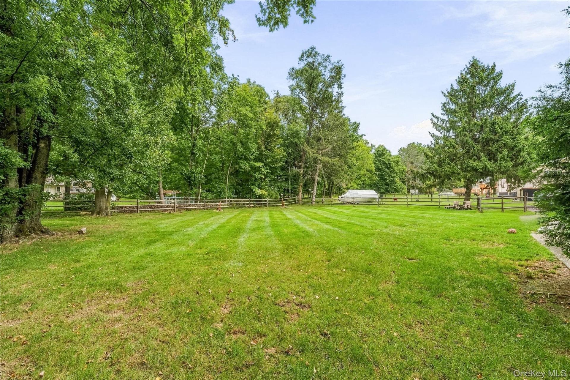 Expansive green lawn with mature trees and perimeter fencing