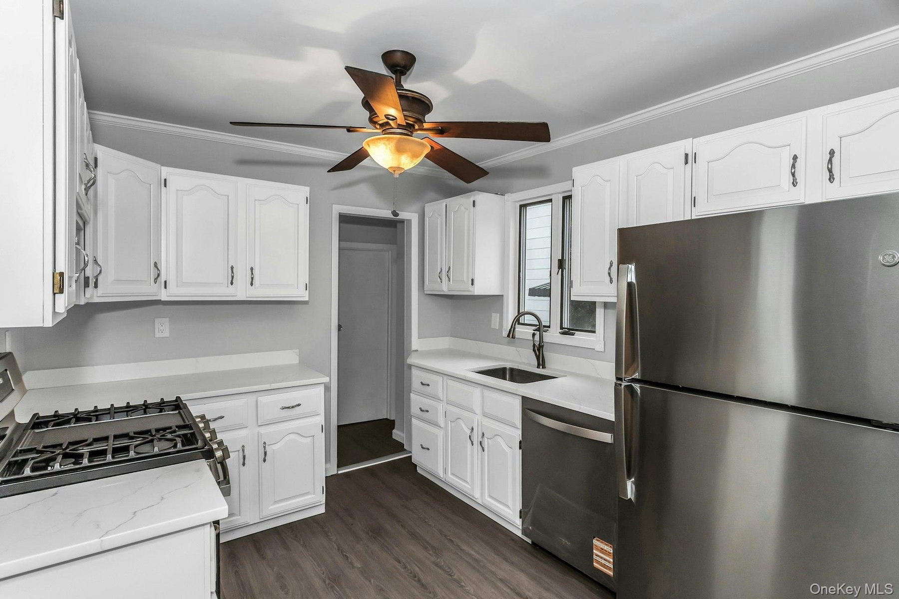 Kitchen featuring white cabinetry, light countertops, wood-finish flooring, stainless steel appliances, and a gas range