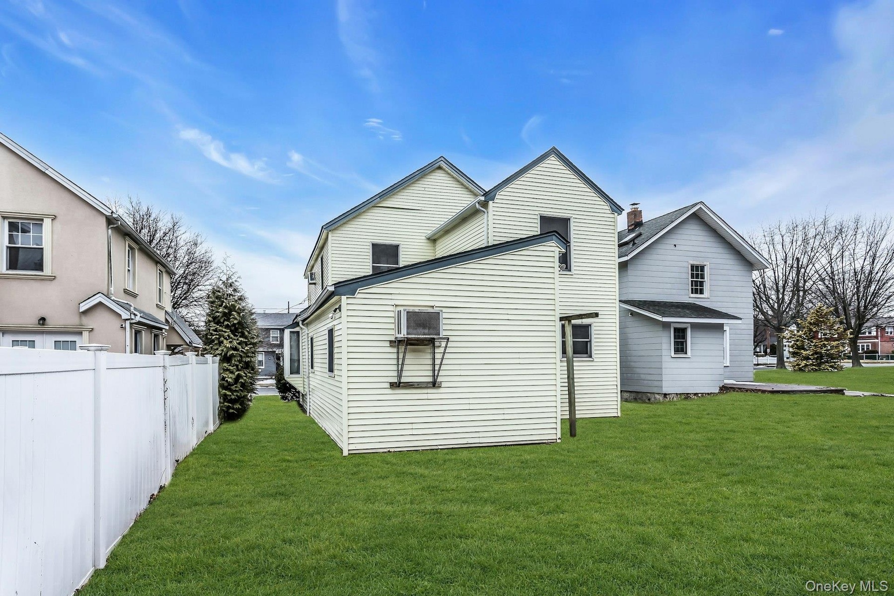 Expansive grassy yard with a white privacy fence