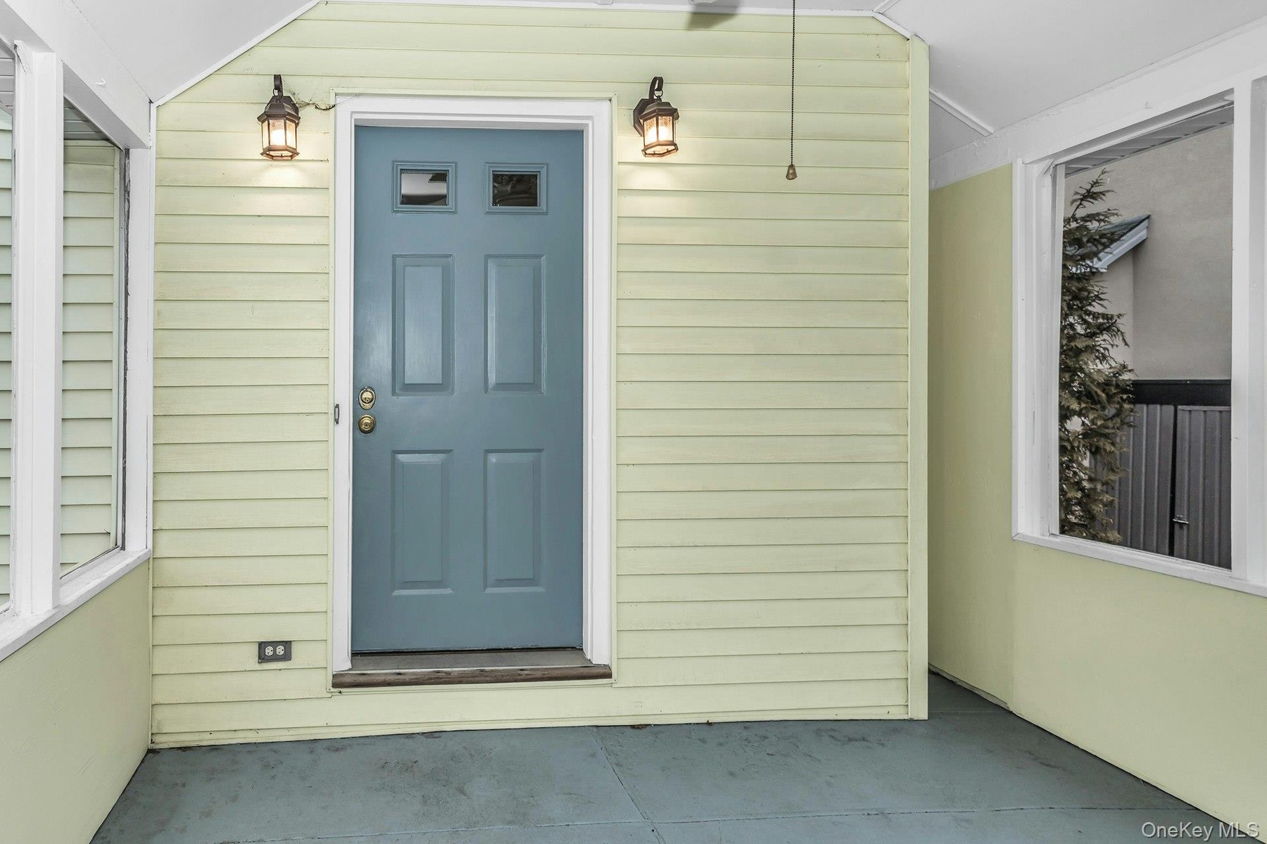 Enclosed porch entry featuring a paneled door with upper glass inserts, two exterior wall lanterns, and a ceiling fan