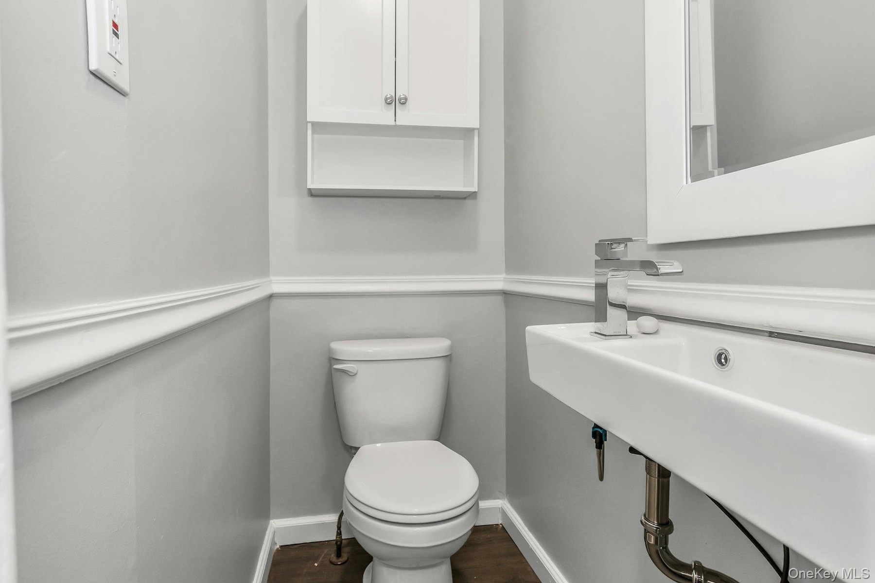 Bathroom featuring a wall-mounted floating sink, chrome faucet, and white wall cabinetry