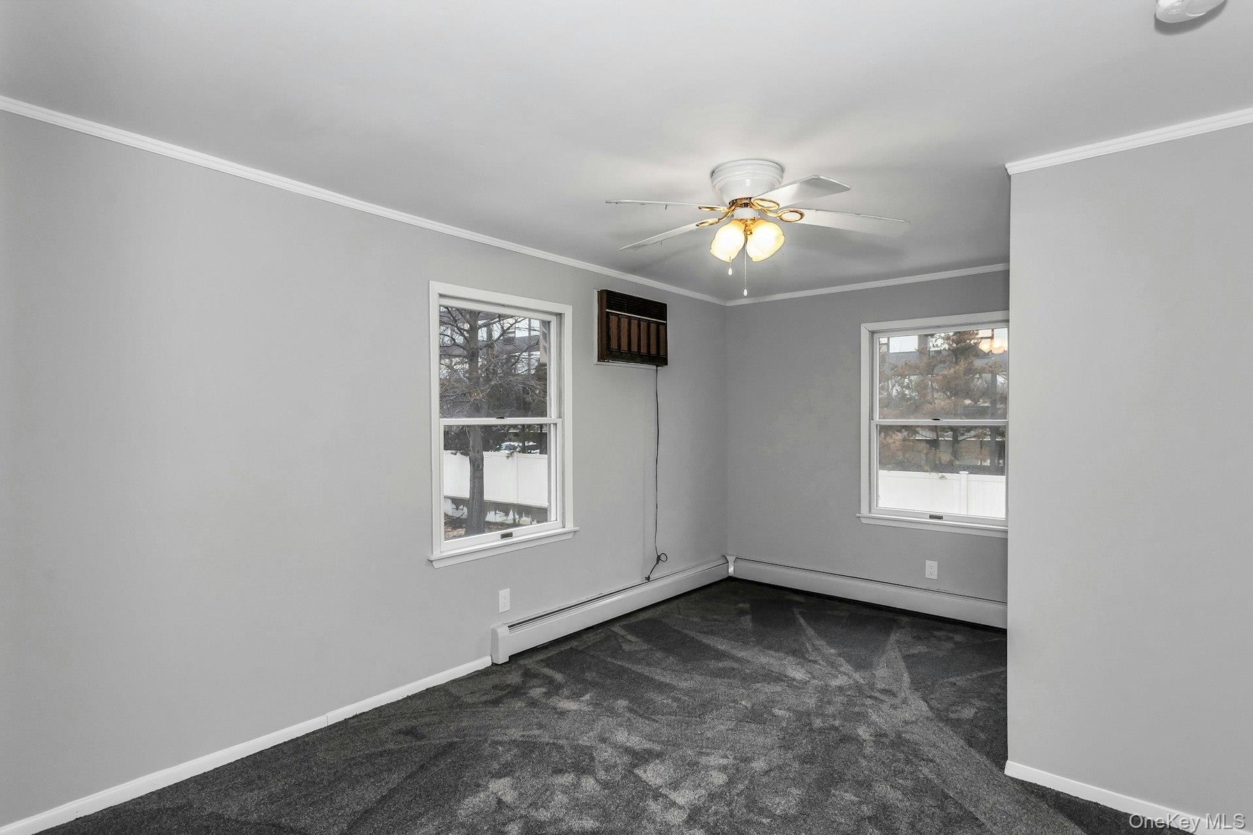 Spacious room featuring light gray walls, dark gray carpeting, and white trim